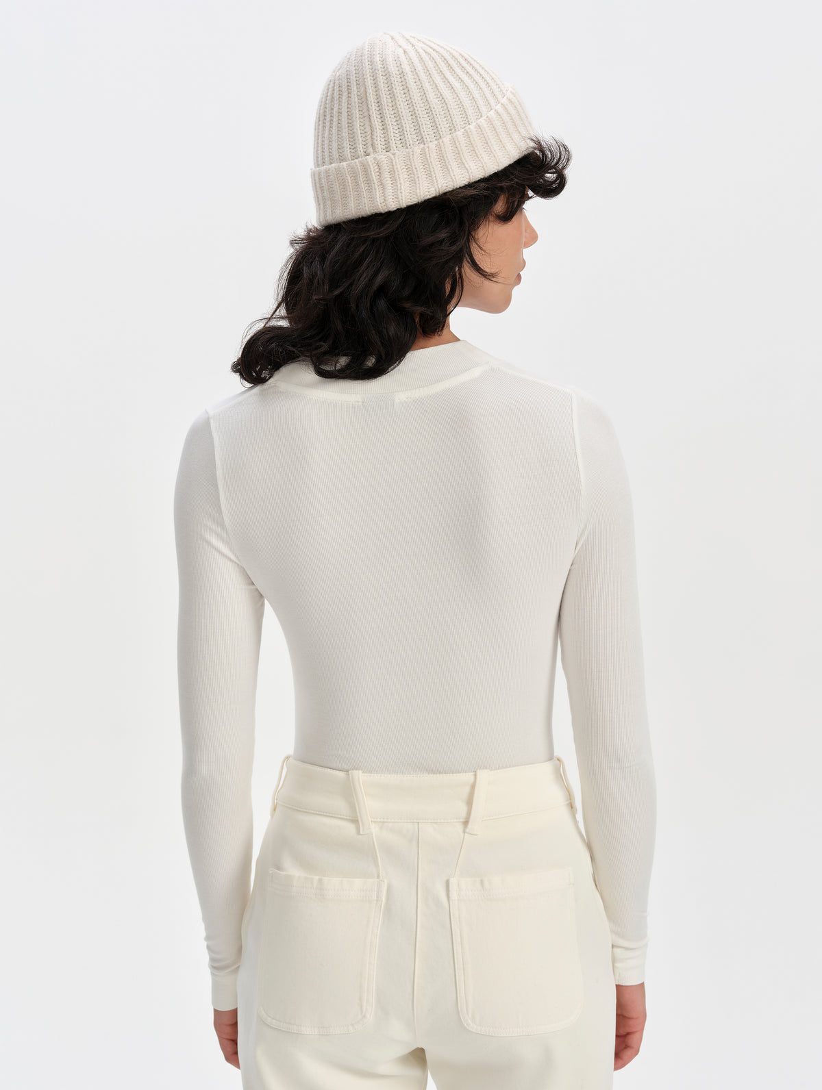 Rear upper-body view of woman wearing the Legacy Long-Sleeve Henley in Winter White from AETHER Apparel.