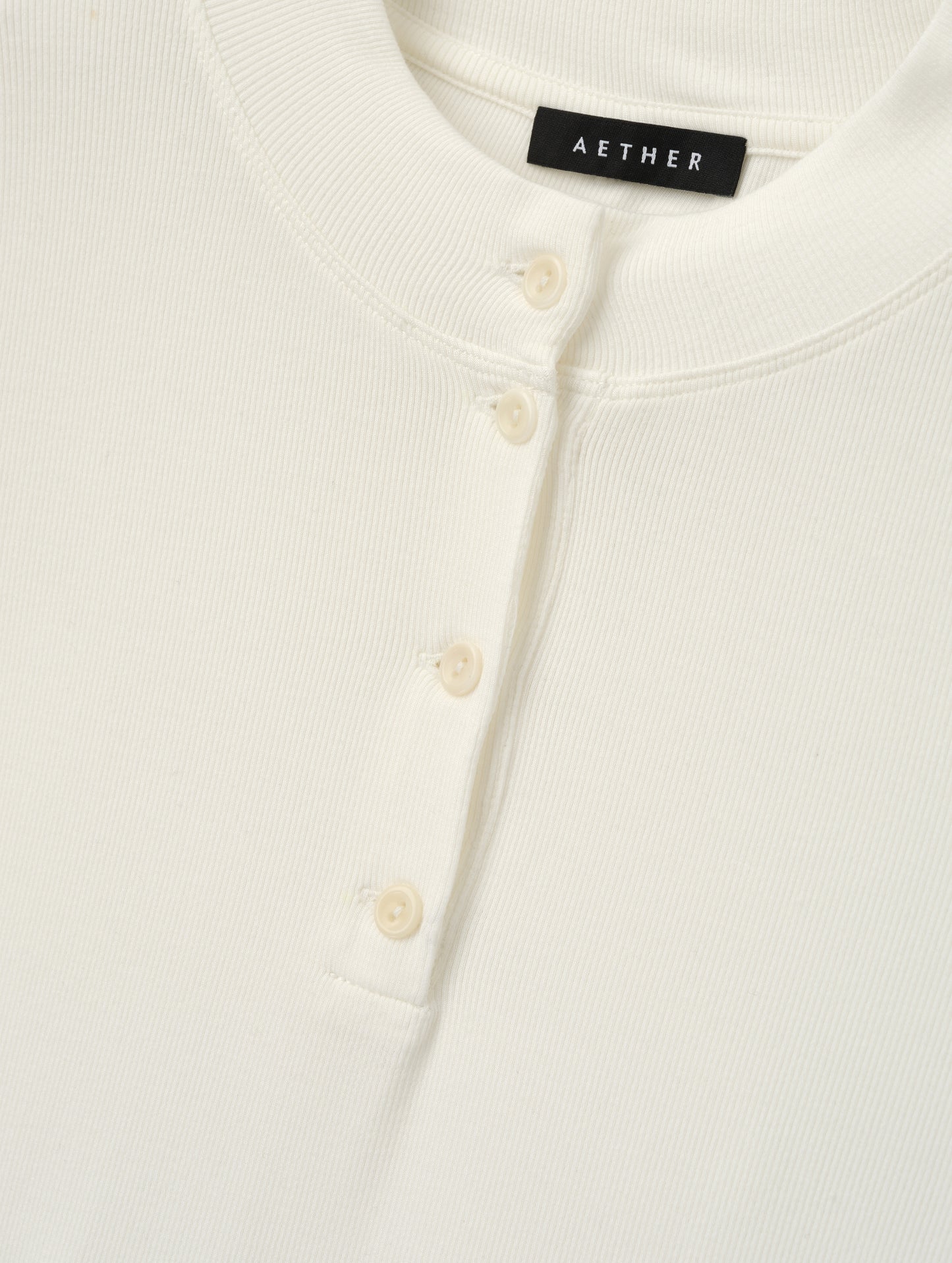 Closeup detailed view of the buttons on the Legacy Long-Sleeve Henley in Winter White from AETHER Apparel.