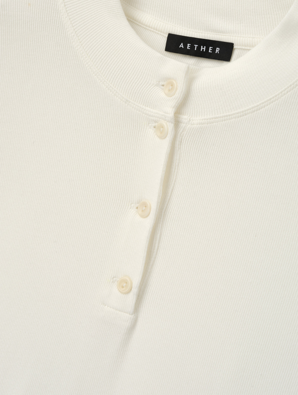 Closeup detailed view of the buttons on the Legacy Long-Sleeve Henley in Winter White from AETHER Apparel.