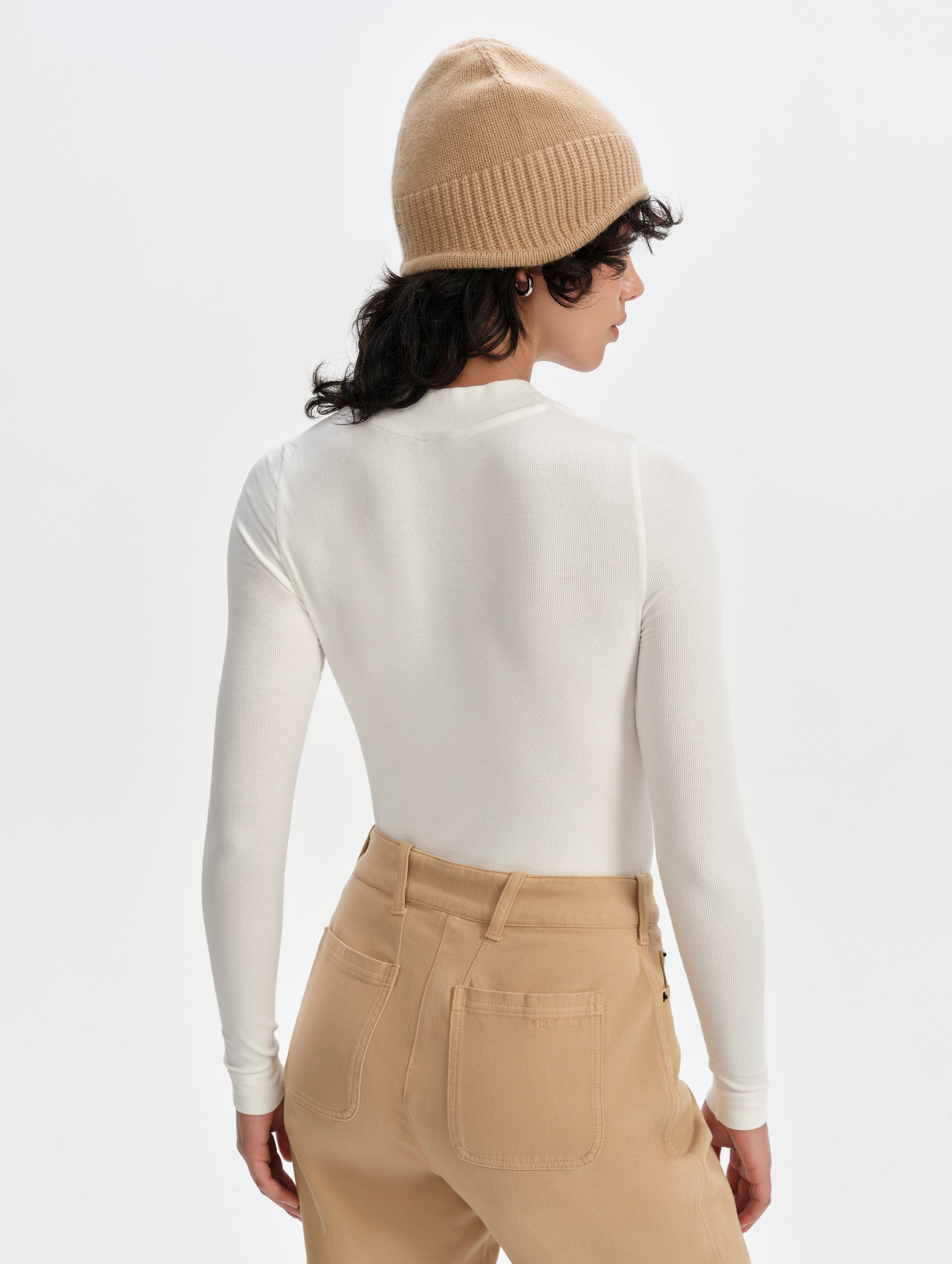 Rear upper-body view of woman wearing the Legacy Long-Sleeve Shirt in Winter White from AETHER Apparel.