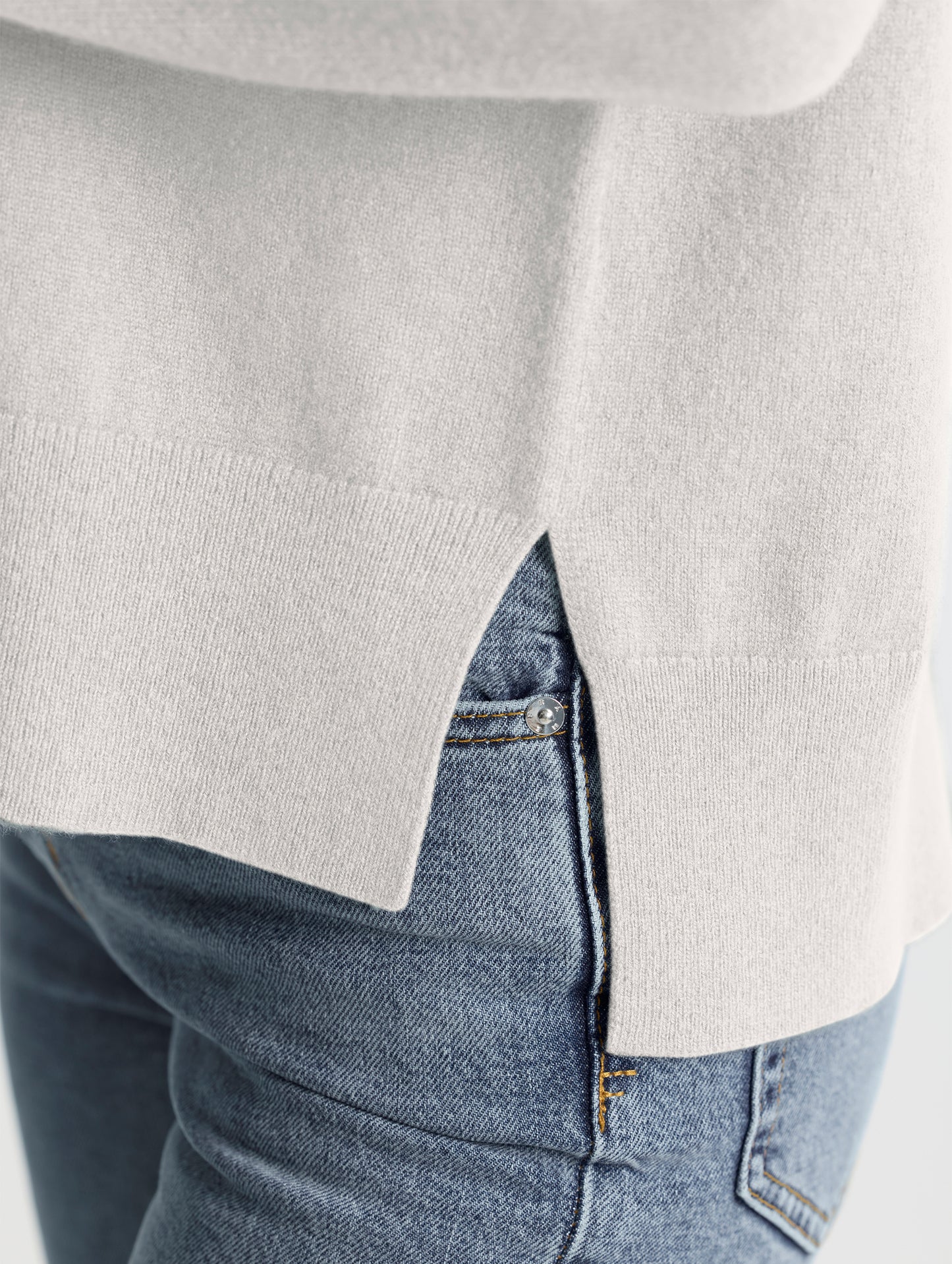 Closeup view of wearer's left side seam split of Leigh Cashmere Crewneck in Winter White from AETHER Apparel.