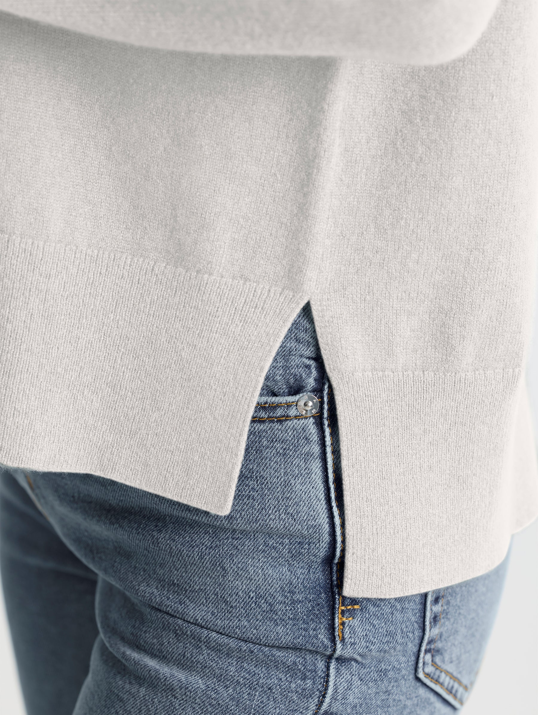 Closeup view of wearer's left side seam split of Leigh Cashmere Crewneck in Winter White from AETHER Apparel.