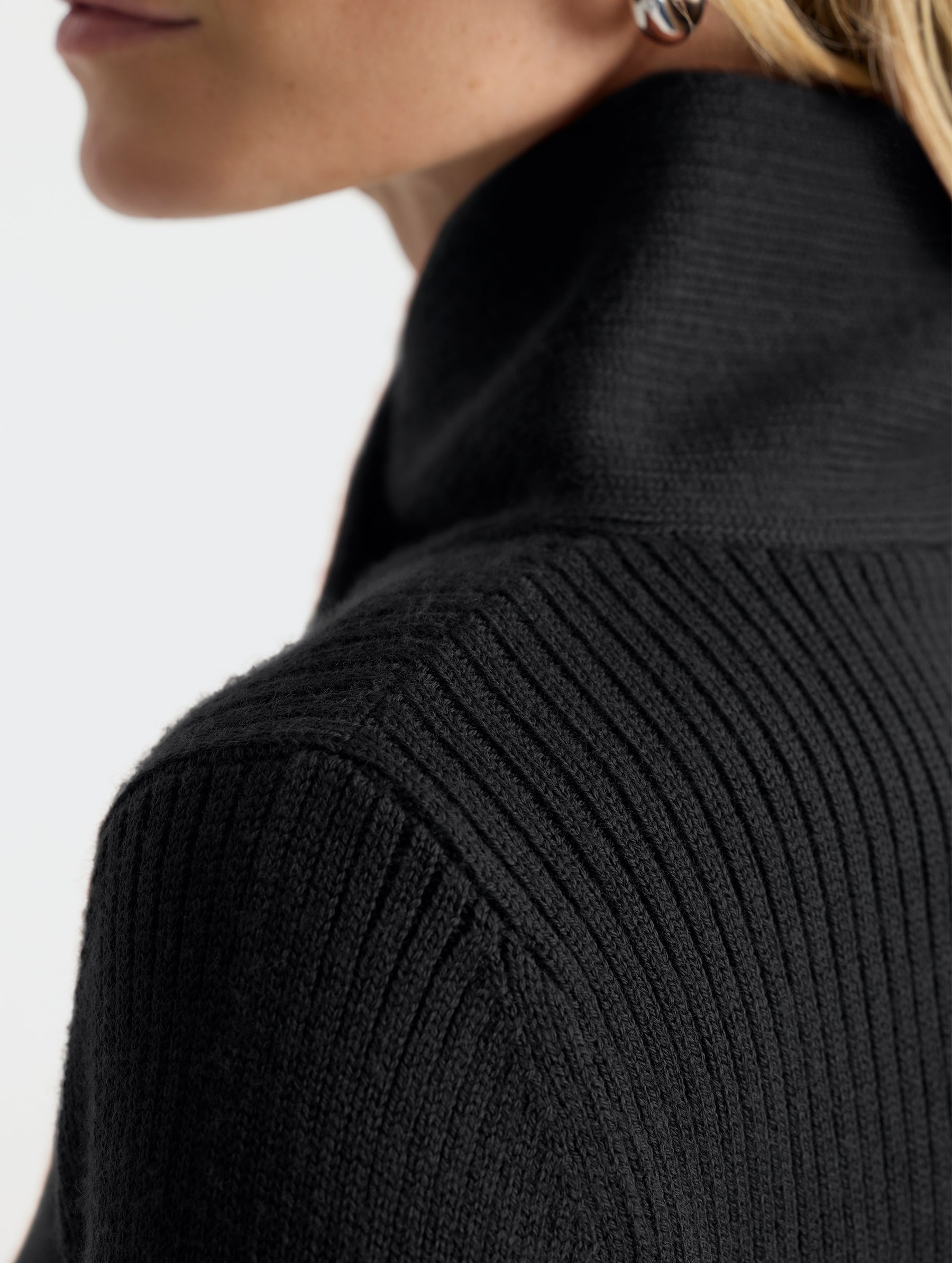 Closeup detail view of wearer's left shoulder stitch of Lexington Sweater in Onyx Black from AETHER Apparel.