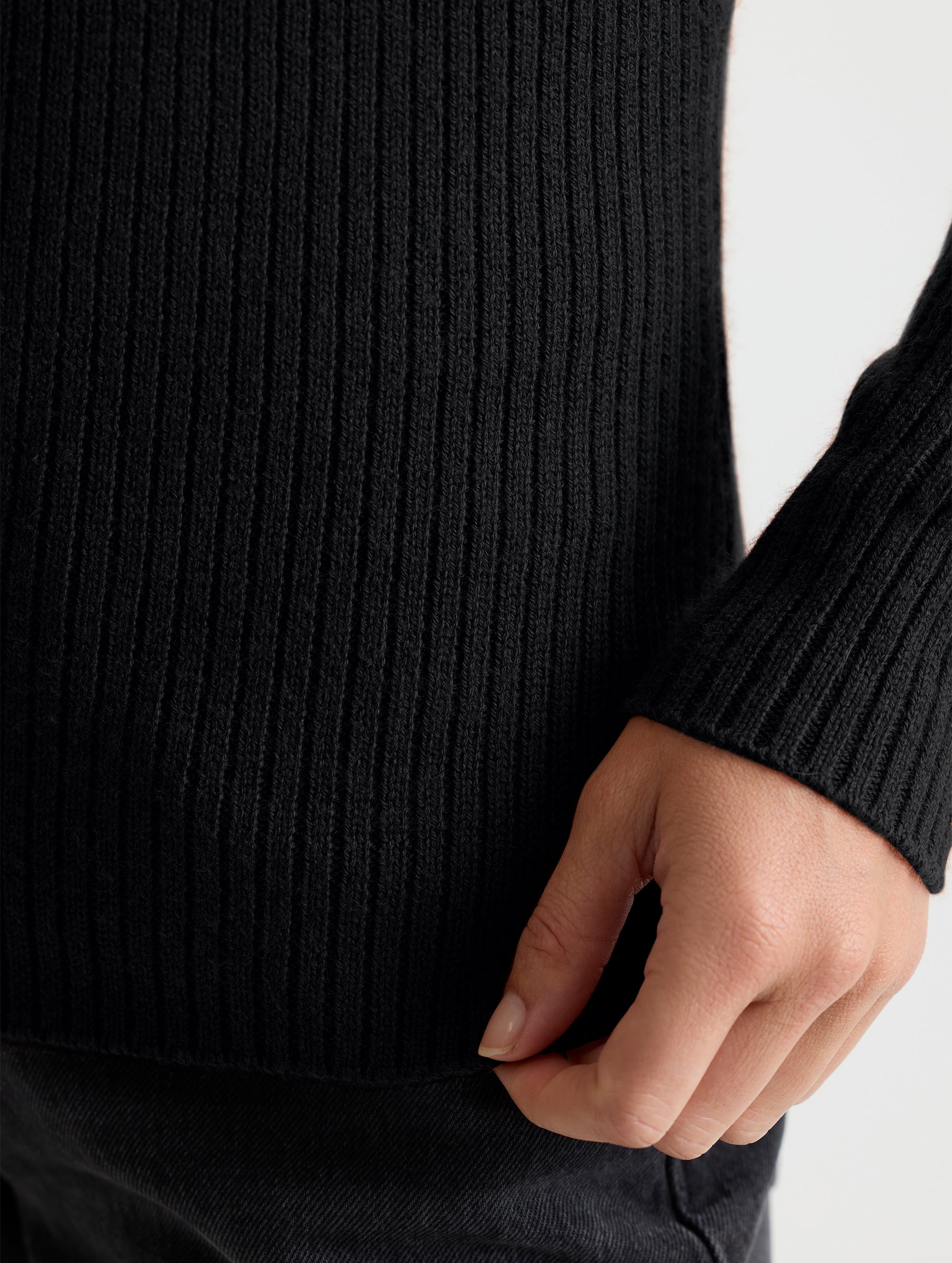 Closeup detail view of wearer's left sleeve of Lexington Sweater in Onyx Black from AETHER Apparel.