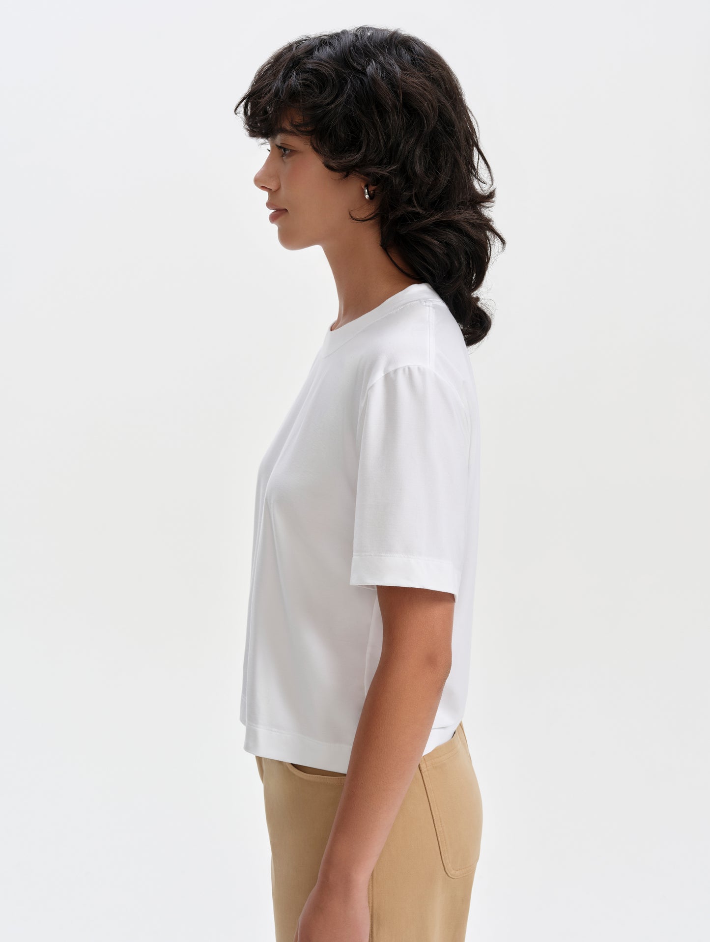 Side profile upper-body view of woman wearing the Lola Relaxed Tee in White from AETHER Apparel.