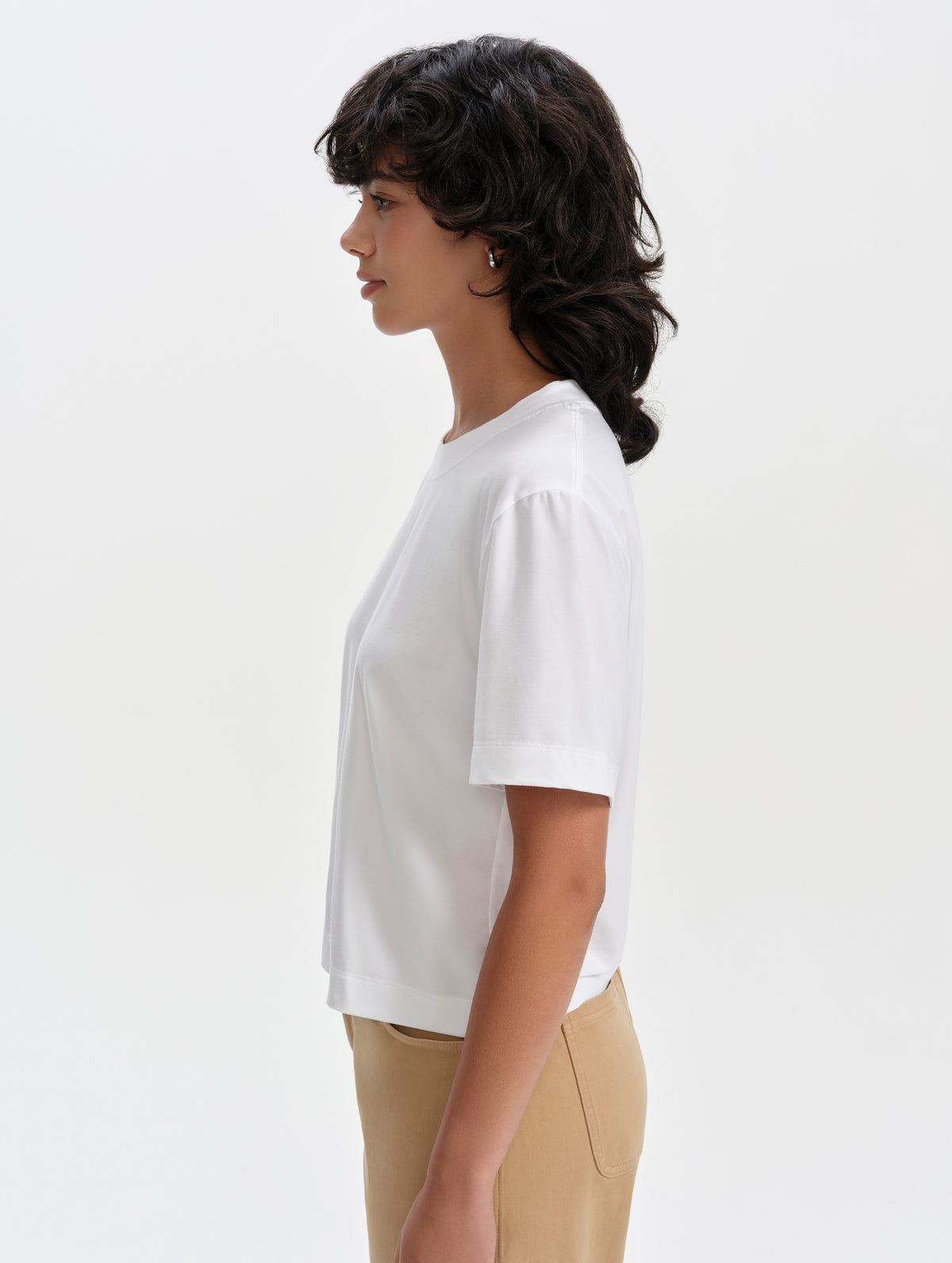 Side profile upper-body view of woman wearing the Lola Relaxed Tee in White from AETHER Apparel.