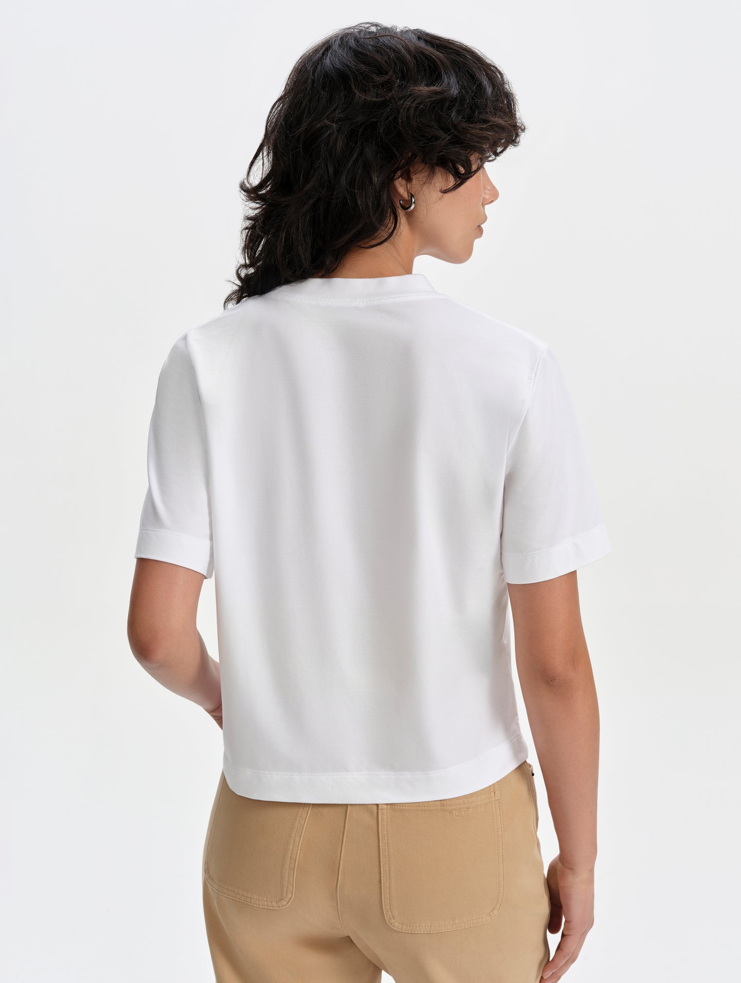 Rear upper-body view of woman wearing the Lola Relaxed Tee in White from AETHER Apparel.