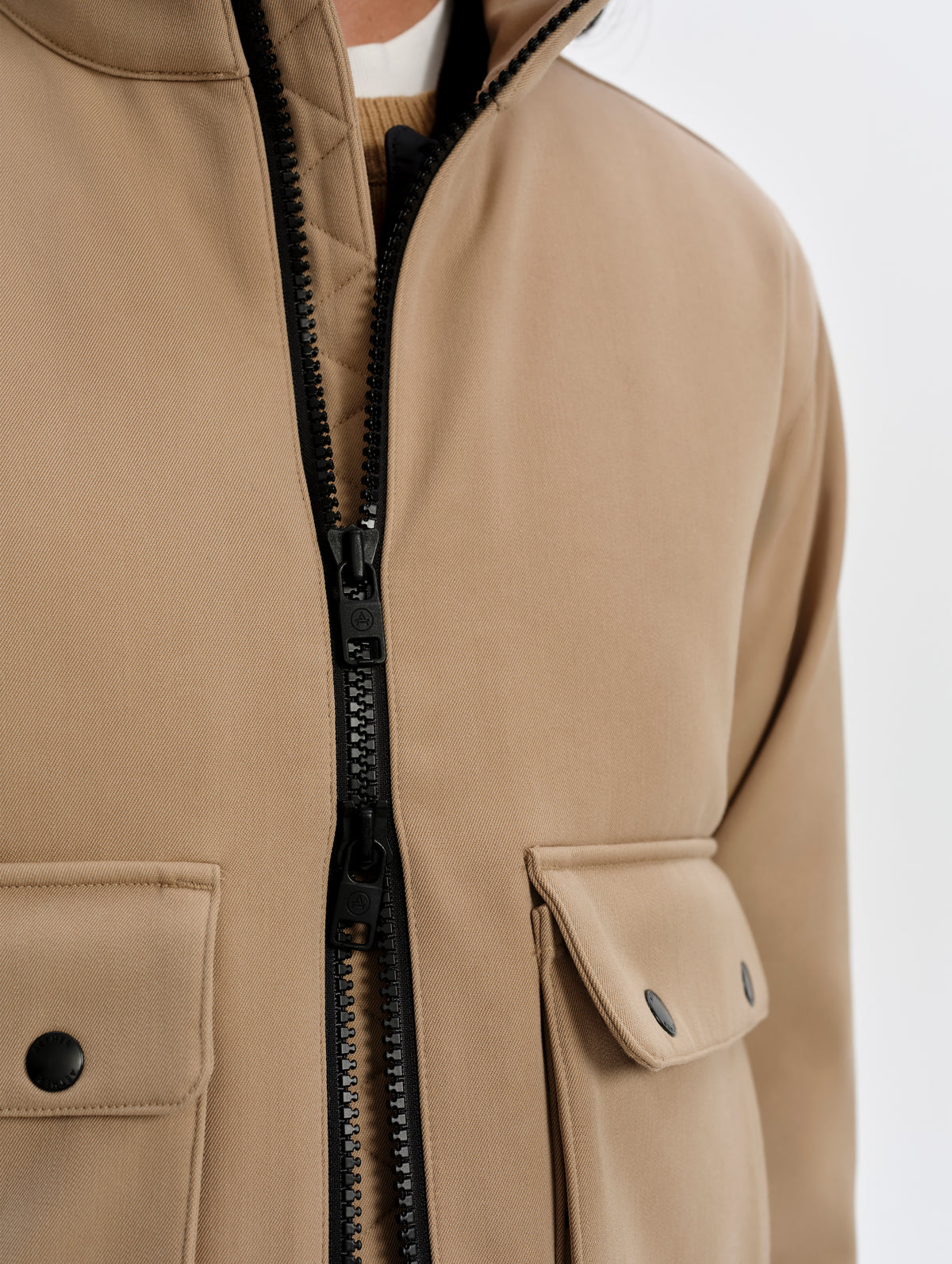 Closeup detailed view of the center-front two-way zipper on the Luna 3-in-1 Field Jacket in Latte Brown from AETHER Apparel.