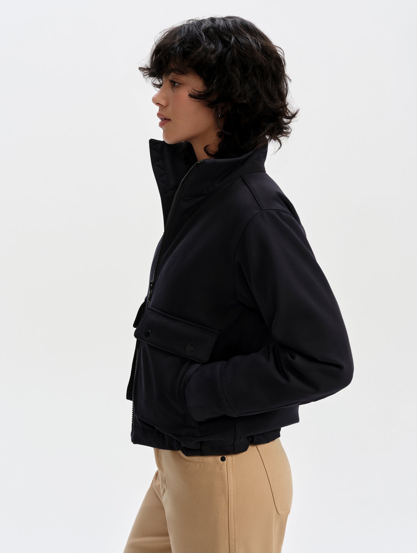 Side profile upper-body view of woman wearing the Luna 3-in-1 Field Jacket in Onyx Black from AETHER Apparel.