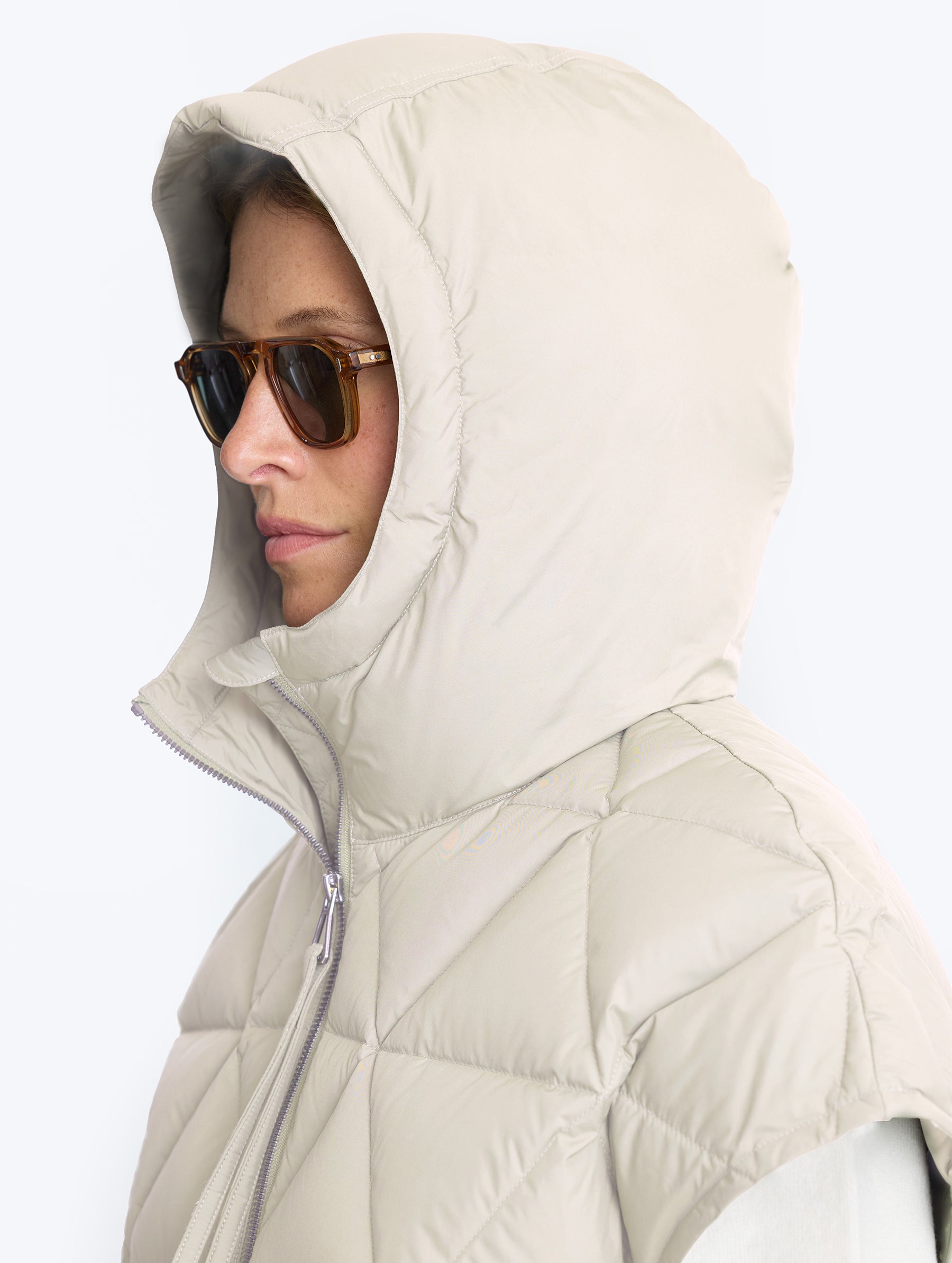 Closeup view of woman wearing hood of Mailen Oversized Vest in Bone White from AETHER Apparel.