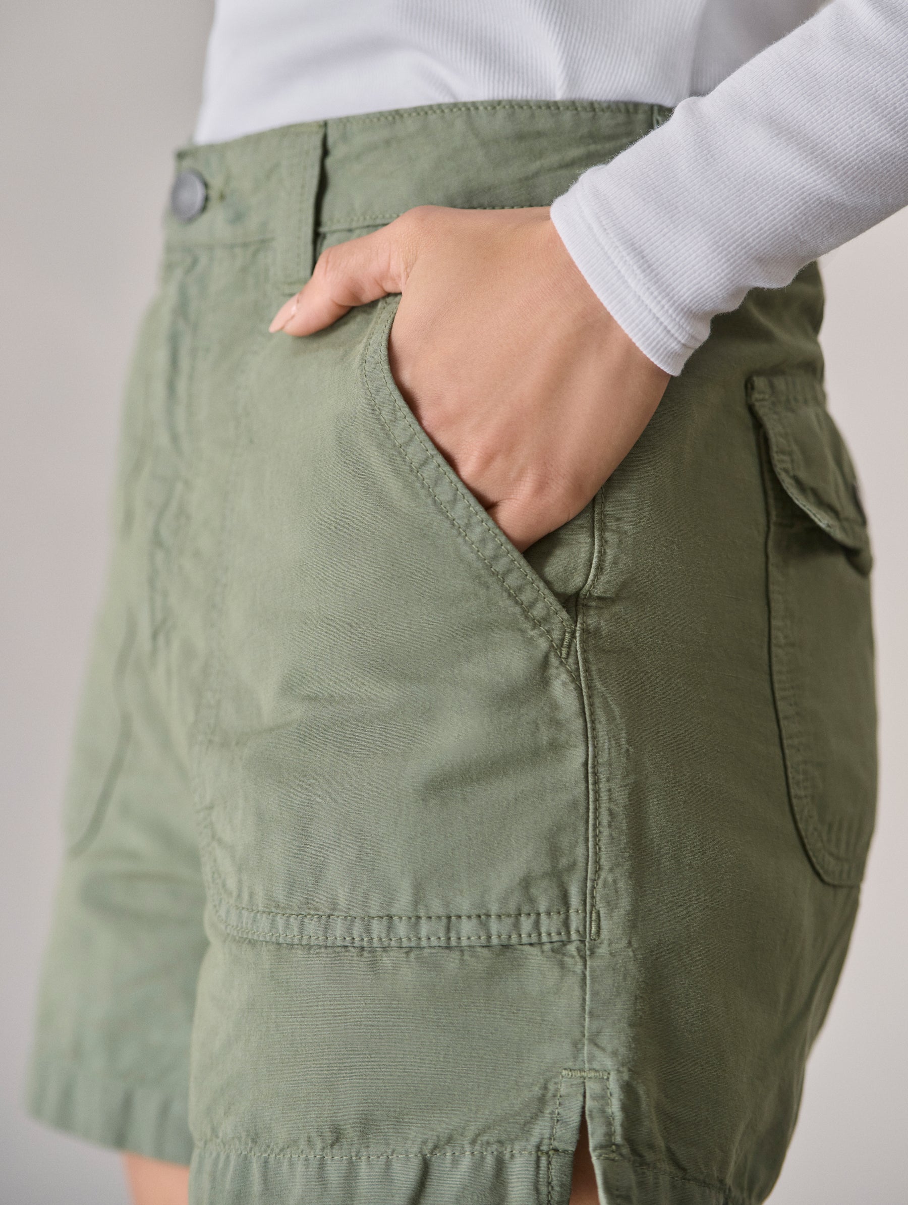 Closeup detailed view of woman with hand in rounded front patch pocket on the Masai Safari Short in Fern Green from AETHER Apparel.