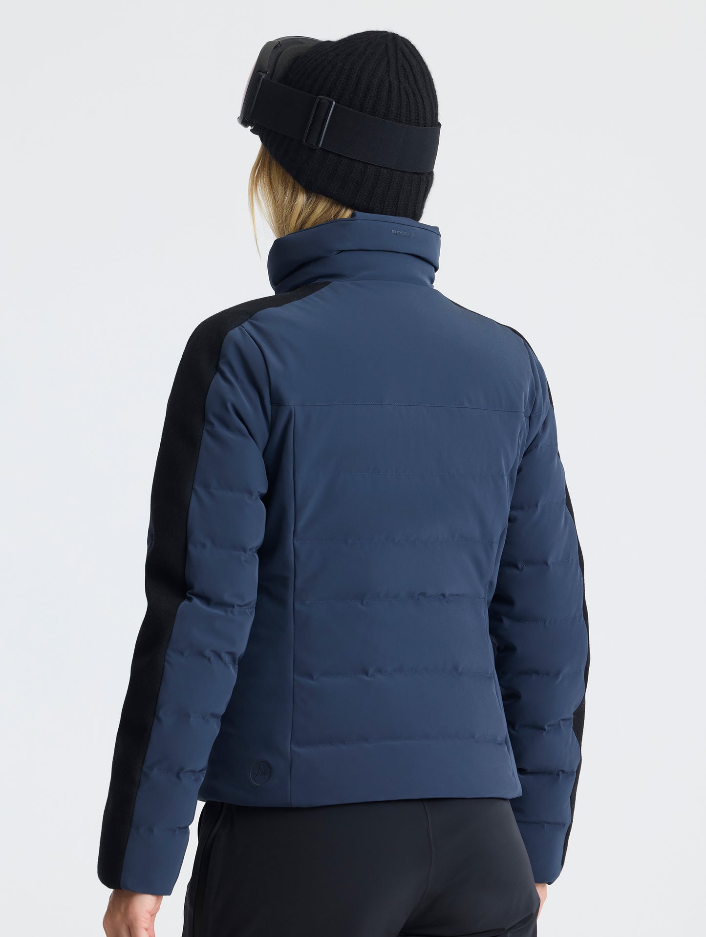 Rear angled upper-body view of woman wearing the Nordic Jacket 2.0 in Total Eclipse dark blue from AETHER Apparel.