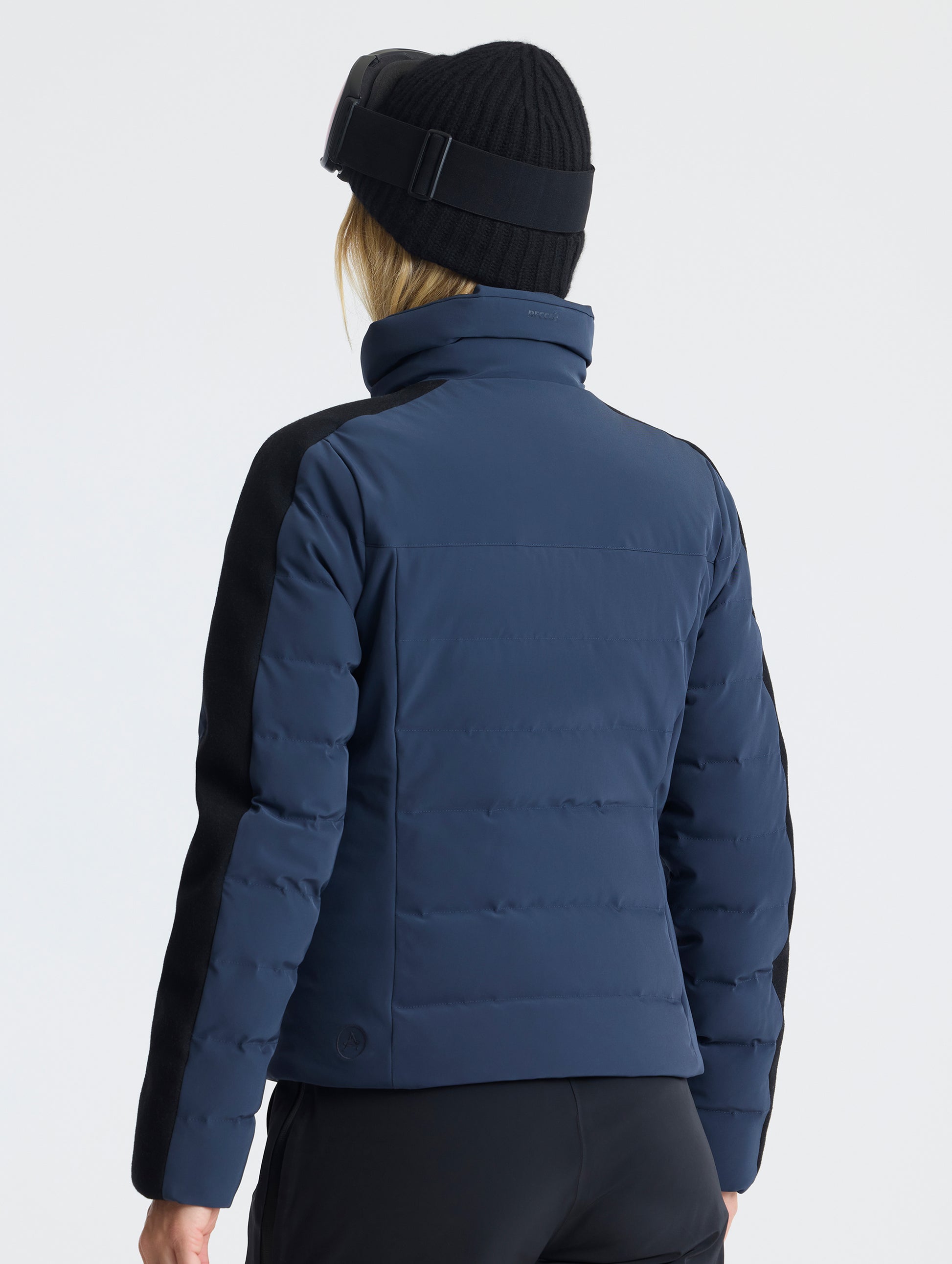 Rear angled upper-body view of woman wearing the Nordic Jacket 2.0 in Total Eclipse dark blue from AETHER Apparel.