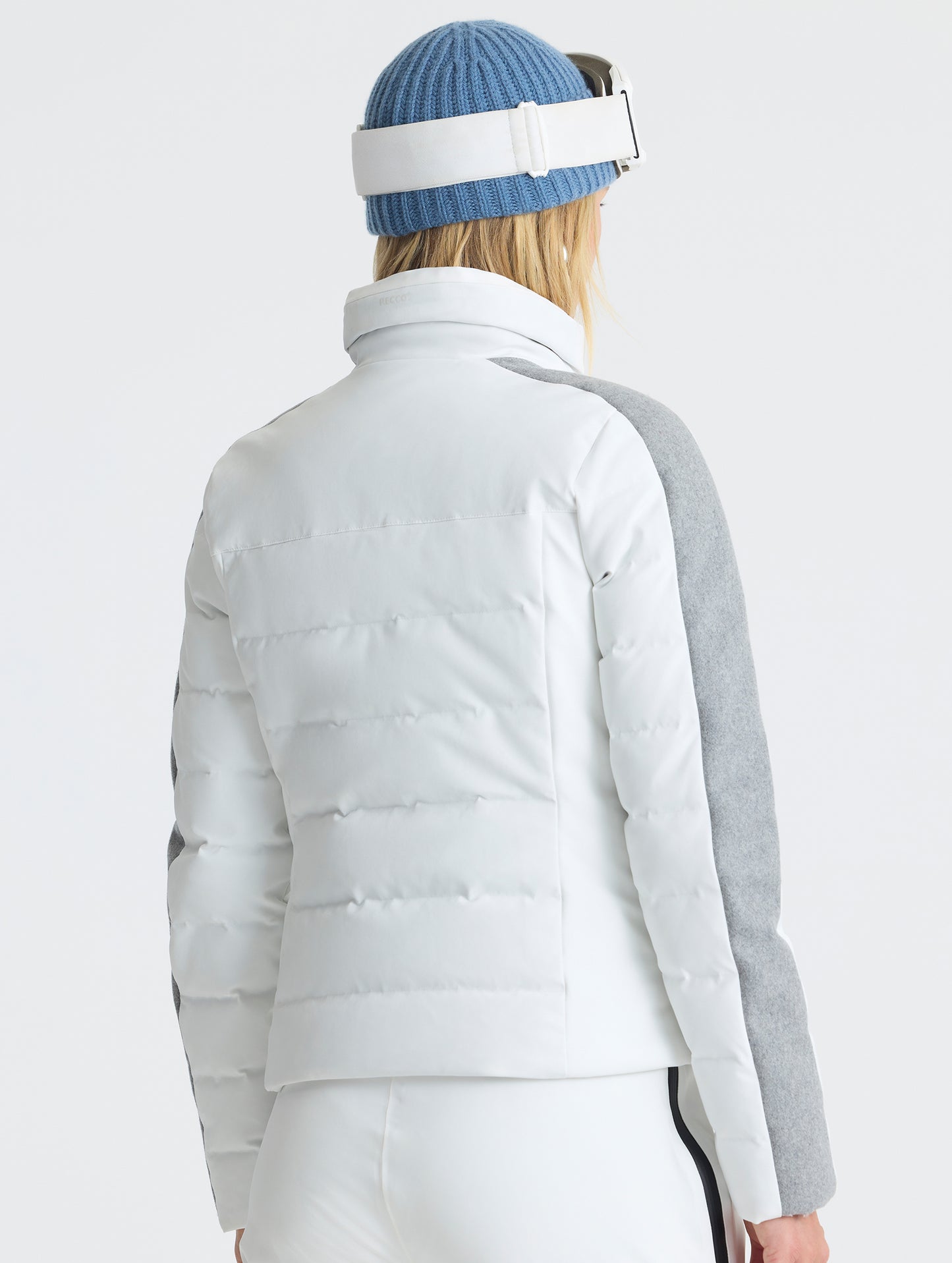 Rear angled upper-body view of woman wearing the Nordic Jacket 2.0 in Winter White from AETHER Apparel.