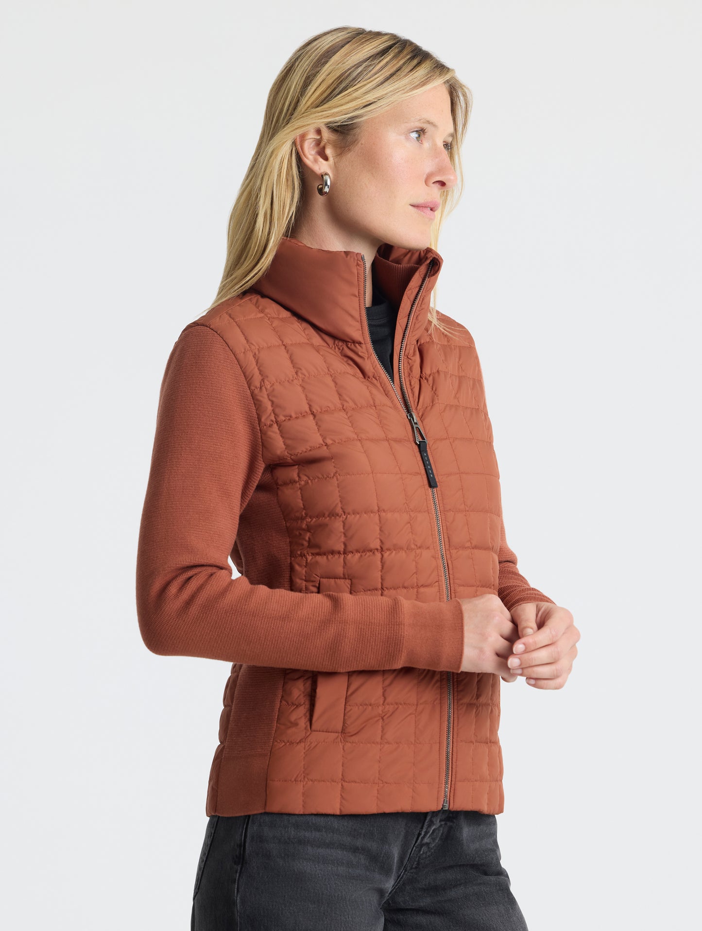 Front, angled, upper-body view of woman wearing Phase Full-Zip in Redwood Rust from AETHER Apparel.