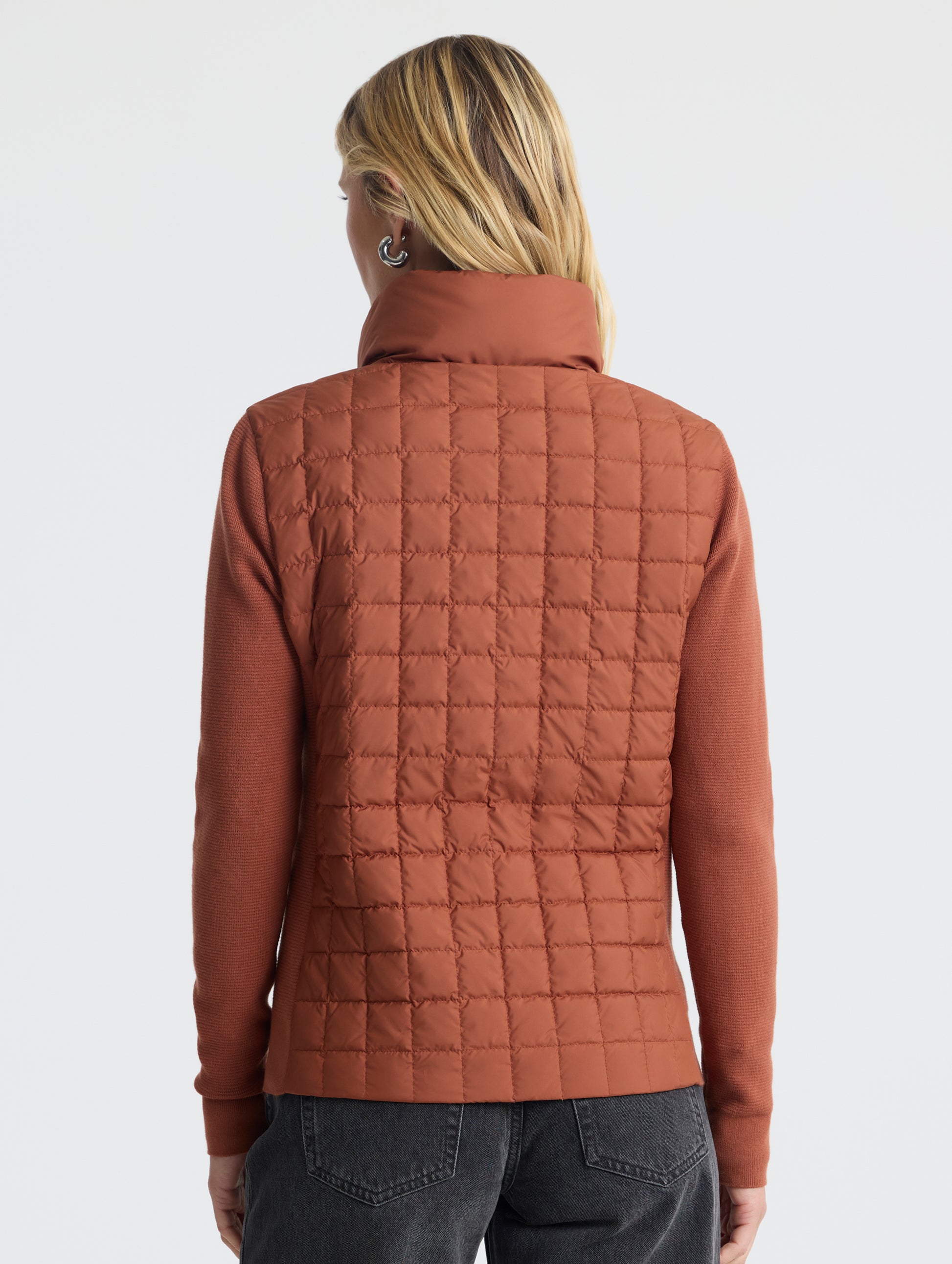 Rear, upper-body view of woman wearing Phase Full-Zip in Redwood Rust from AETHER Apparel.