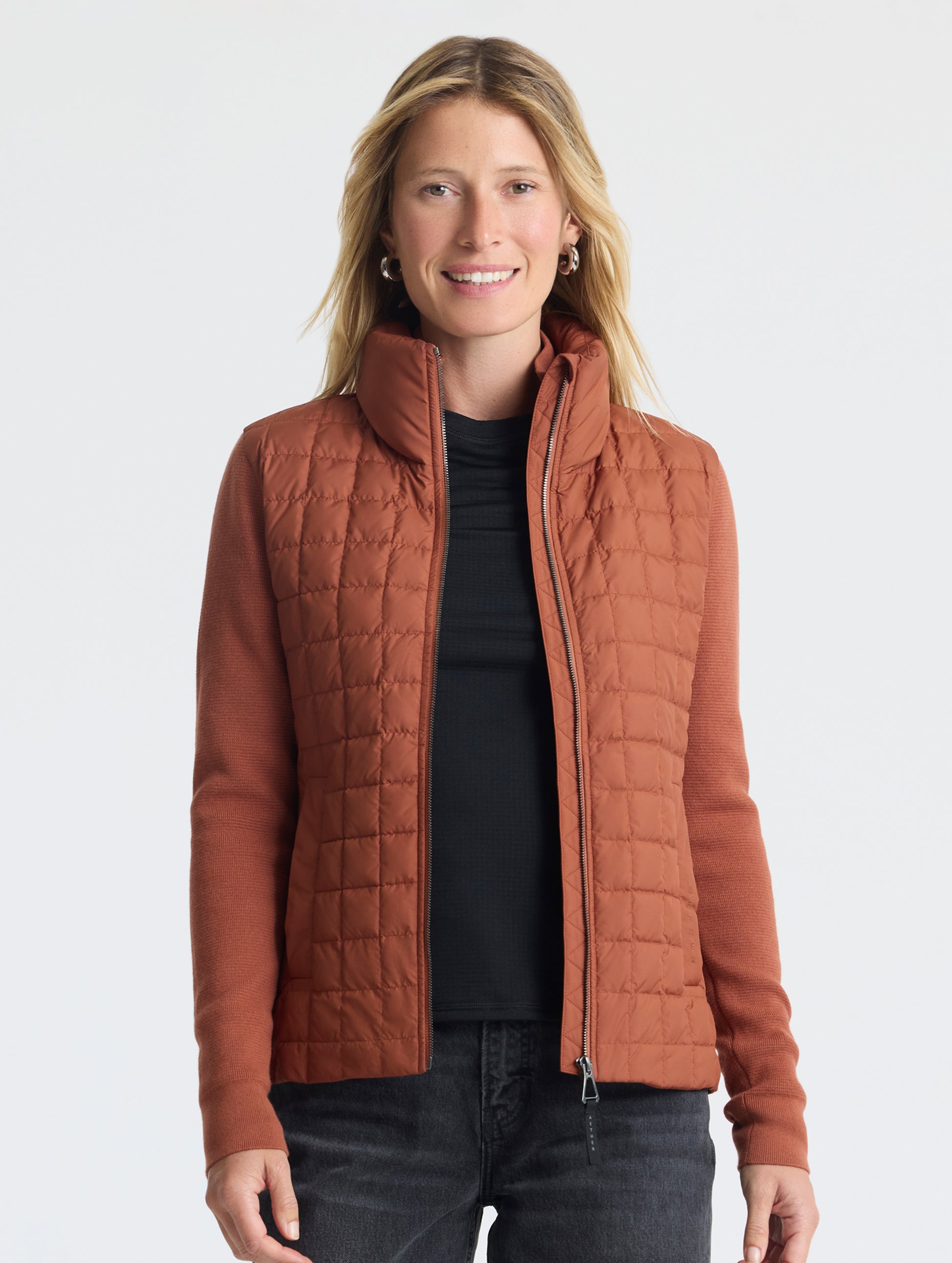 Front, upper-body view of woman wearing unzipped Phase Full-Zip in Redwood Rust from AETHER Apparel.