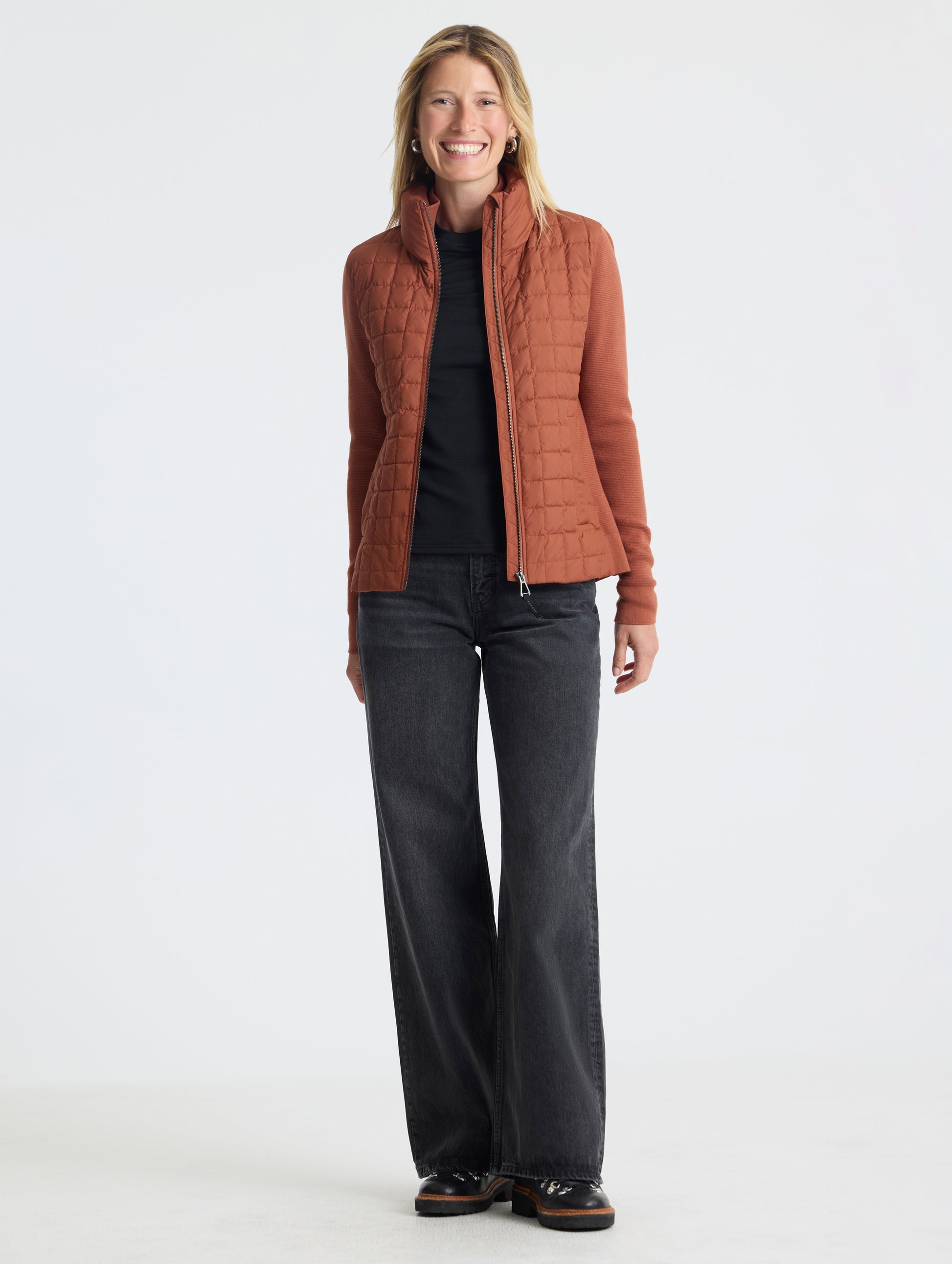 Front, full-body view of woman wearing unzipped Phase Full-Zip in Redwood Rust from AETHER Apparel.