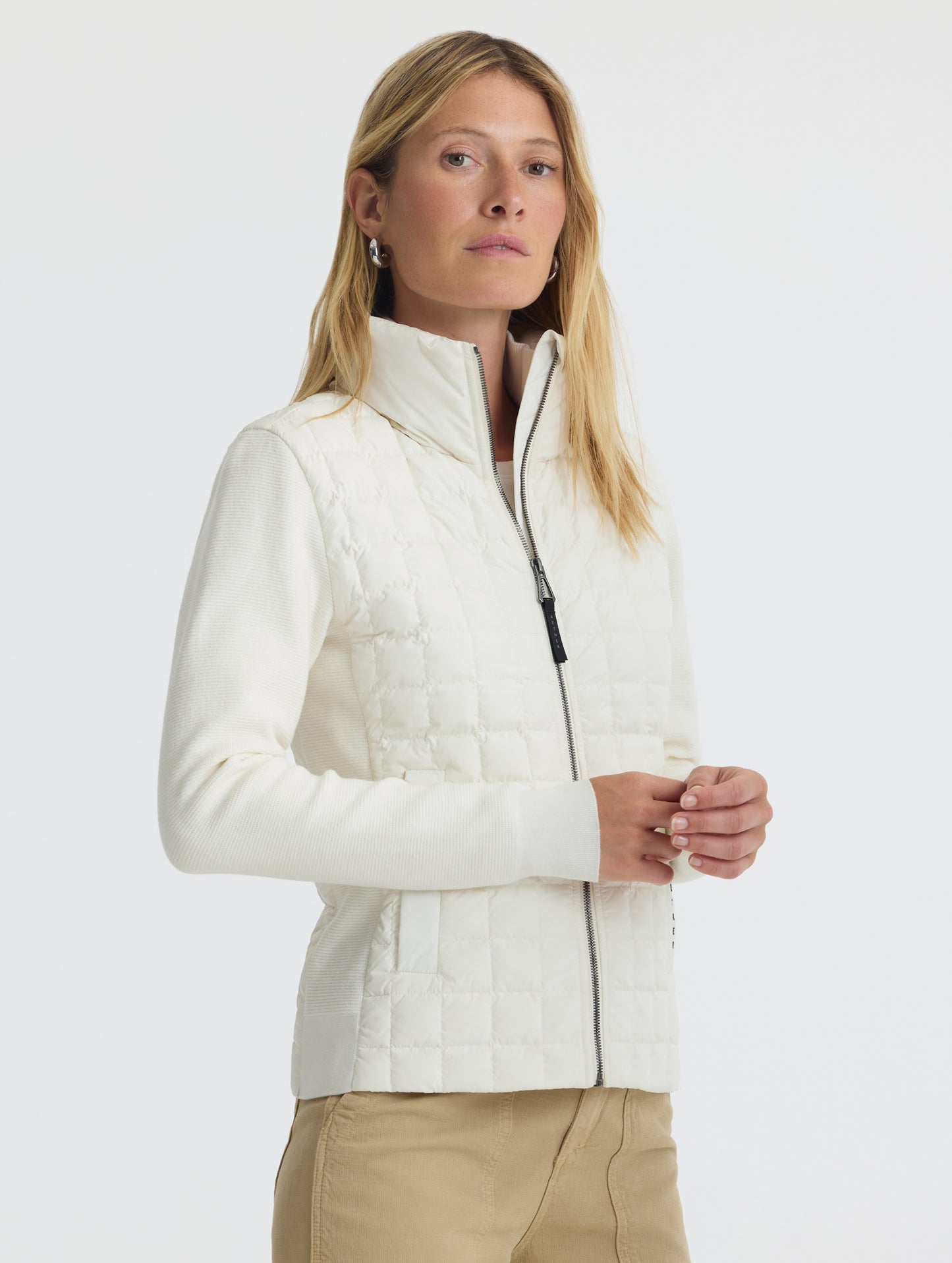 Front, angled, upper-body view of woman wearing Phase Full-Zip in Winter White from AETHER Apparel.