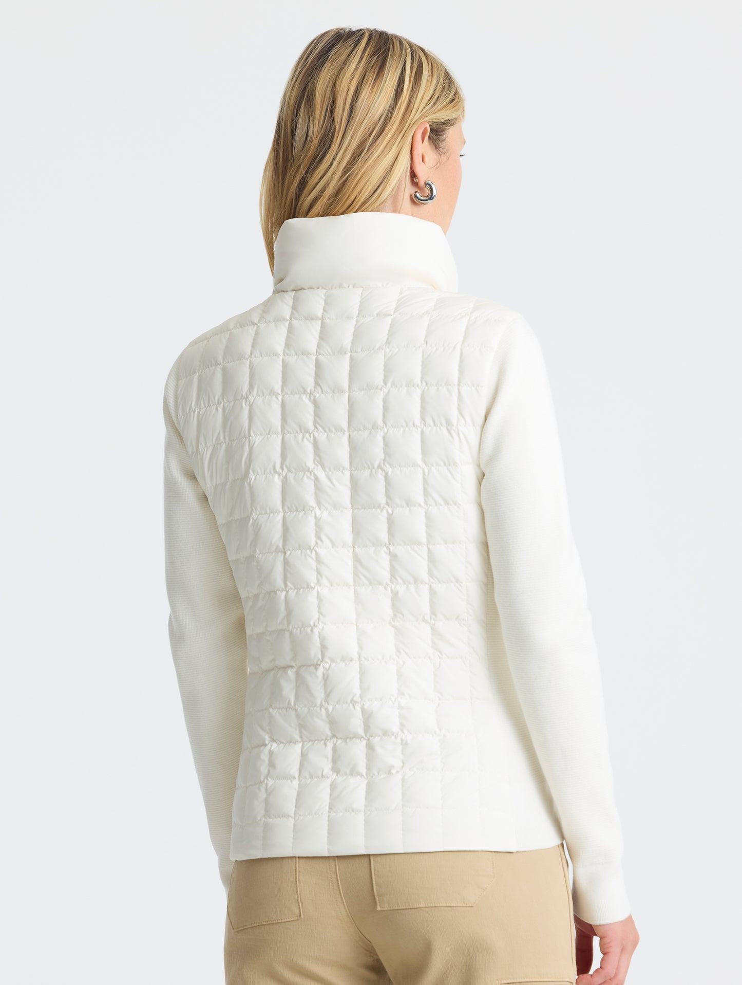 Rear, angled, upper-body view of woman wearing Phase Full-Zip in Winter White from AETHER Apparel.