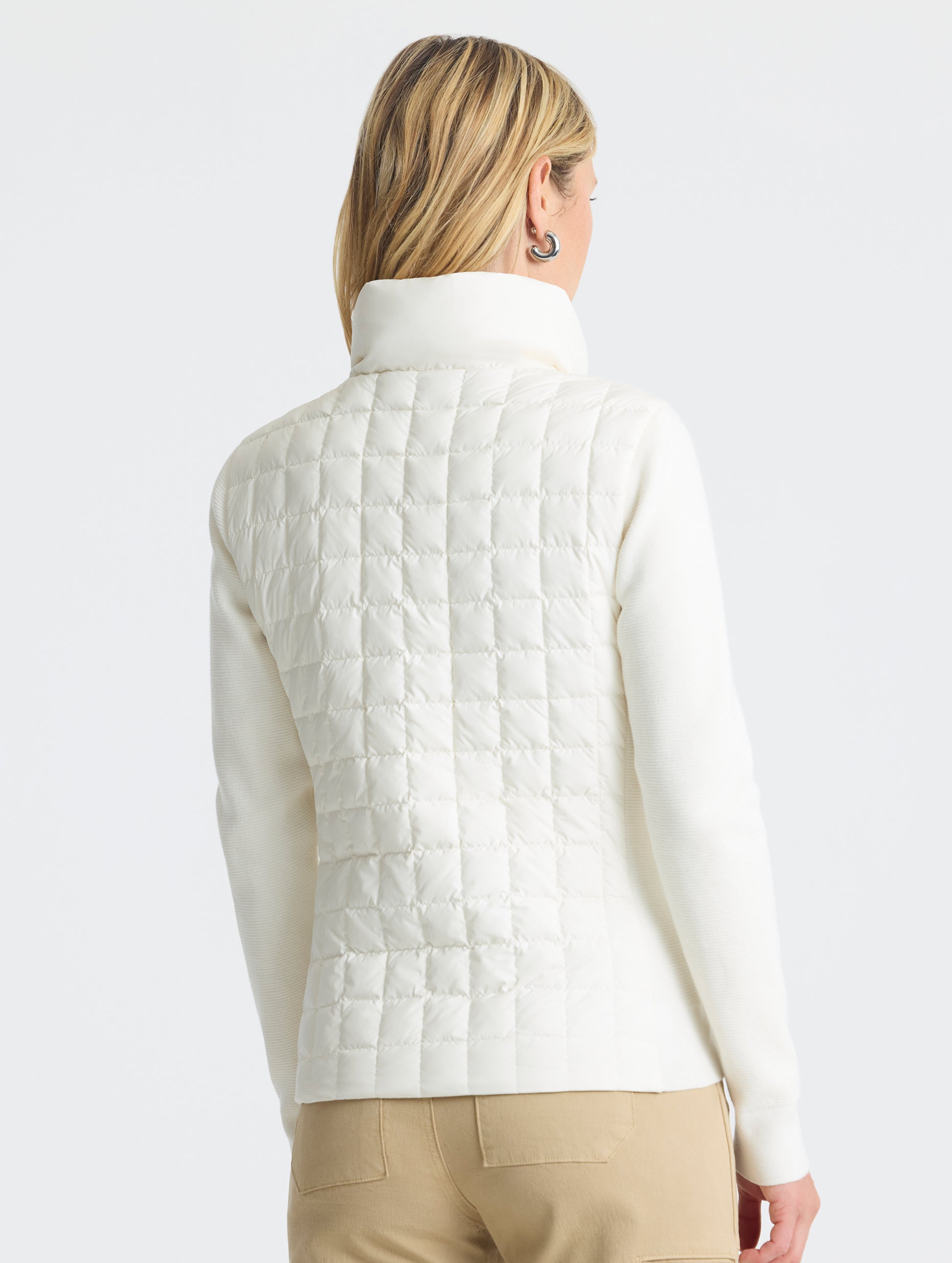 Rear, angled, upper-body view of woman wearing Phase Full-Zip in Winter White from AETHER Apparel.
