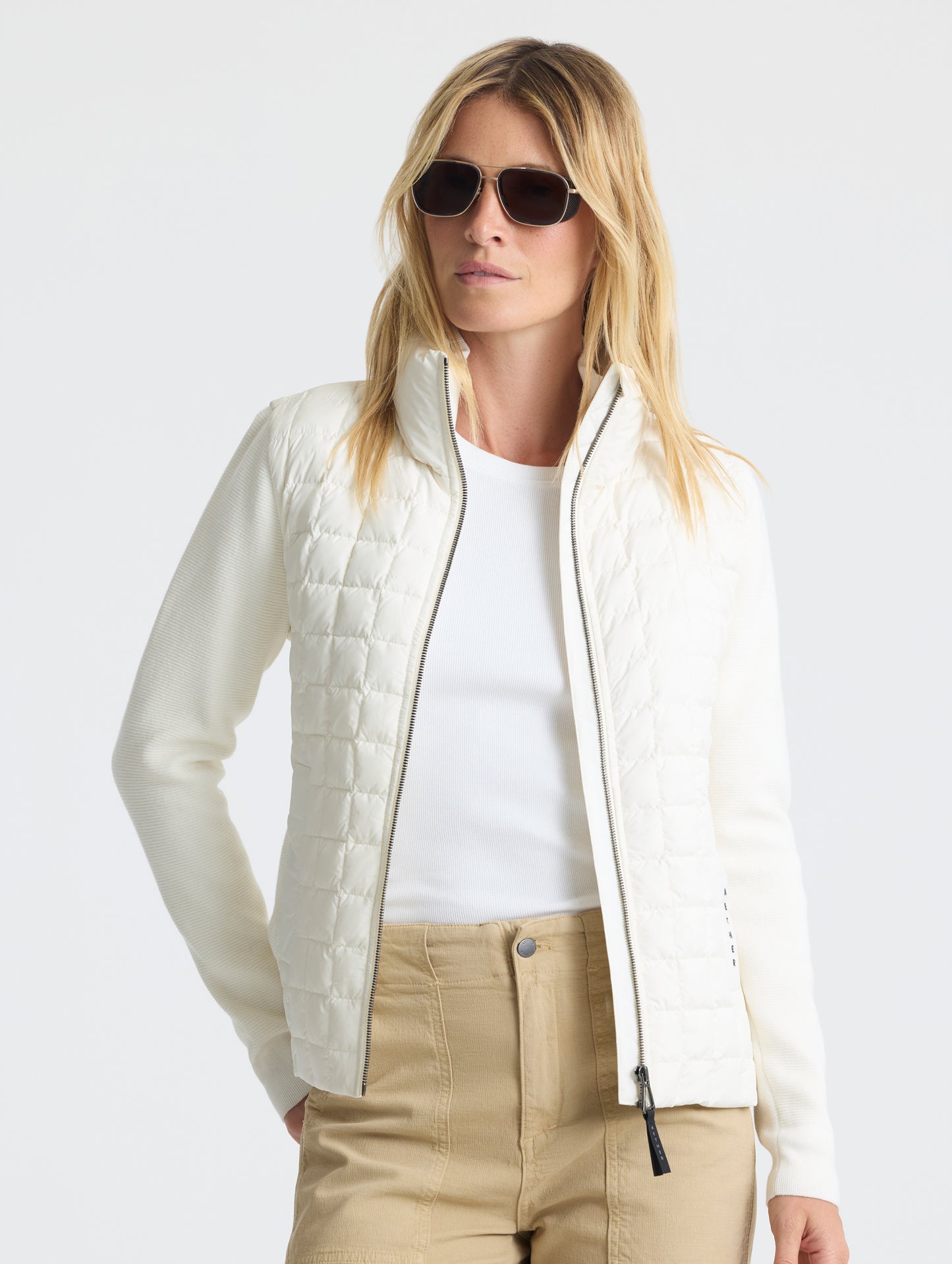 Front upper-body view of woman wearing unzipped Phase Full-Zip in Winter White from AETHER Apparel.