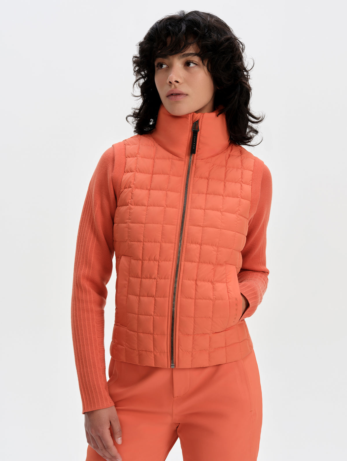 Front upper-body view of woman wearing the Phase Vest in Madeira Orange from AETHER Apparel.