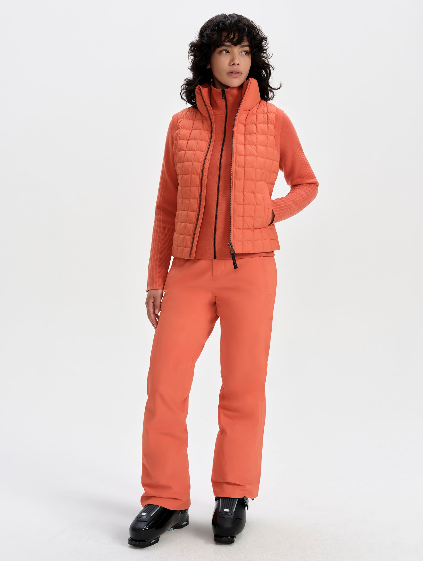 Front full-body view of woman wearing the Phase Vest in Madeira Orange from AETHER Apparel.