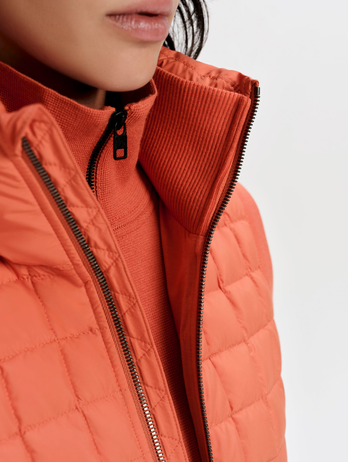 Closeup detailed view of the center-front zipper and inner and outer collars on the Phase Vest in Madeira Orange from AETHER Apparel.