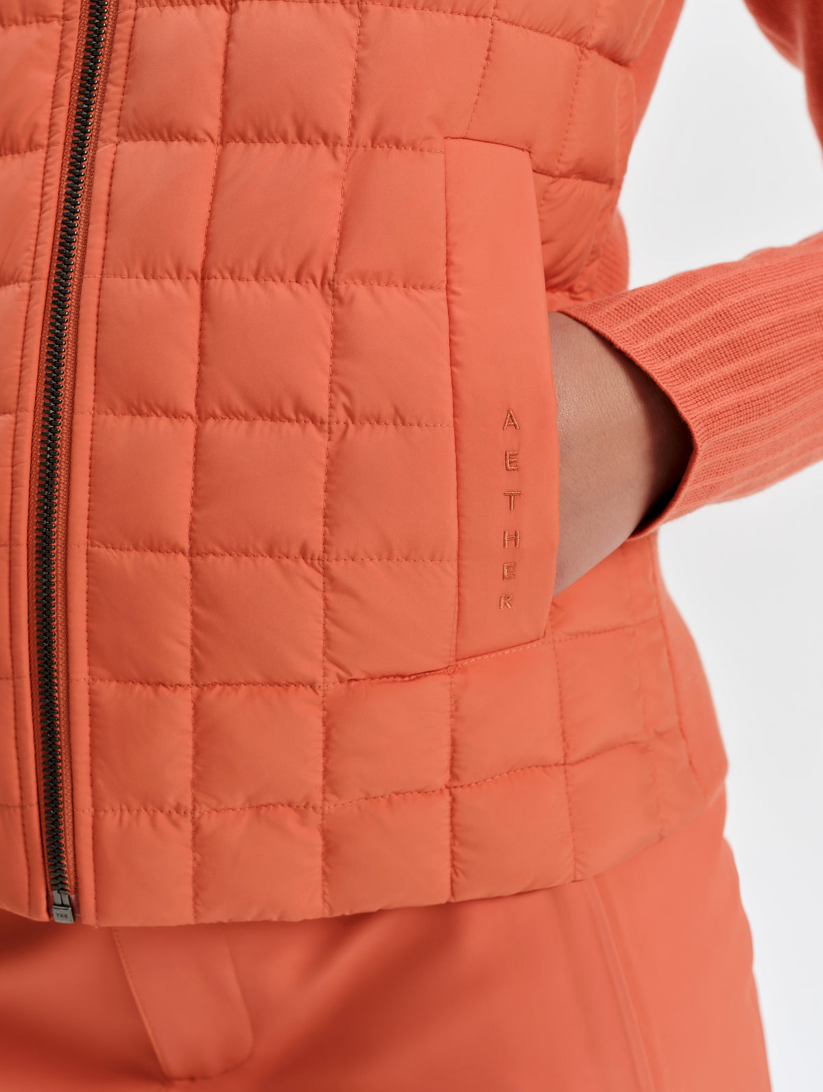 Closeup detailed view of the hand pocket on the Phase Vest in Madeira Orange from AETHER Apparel.