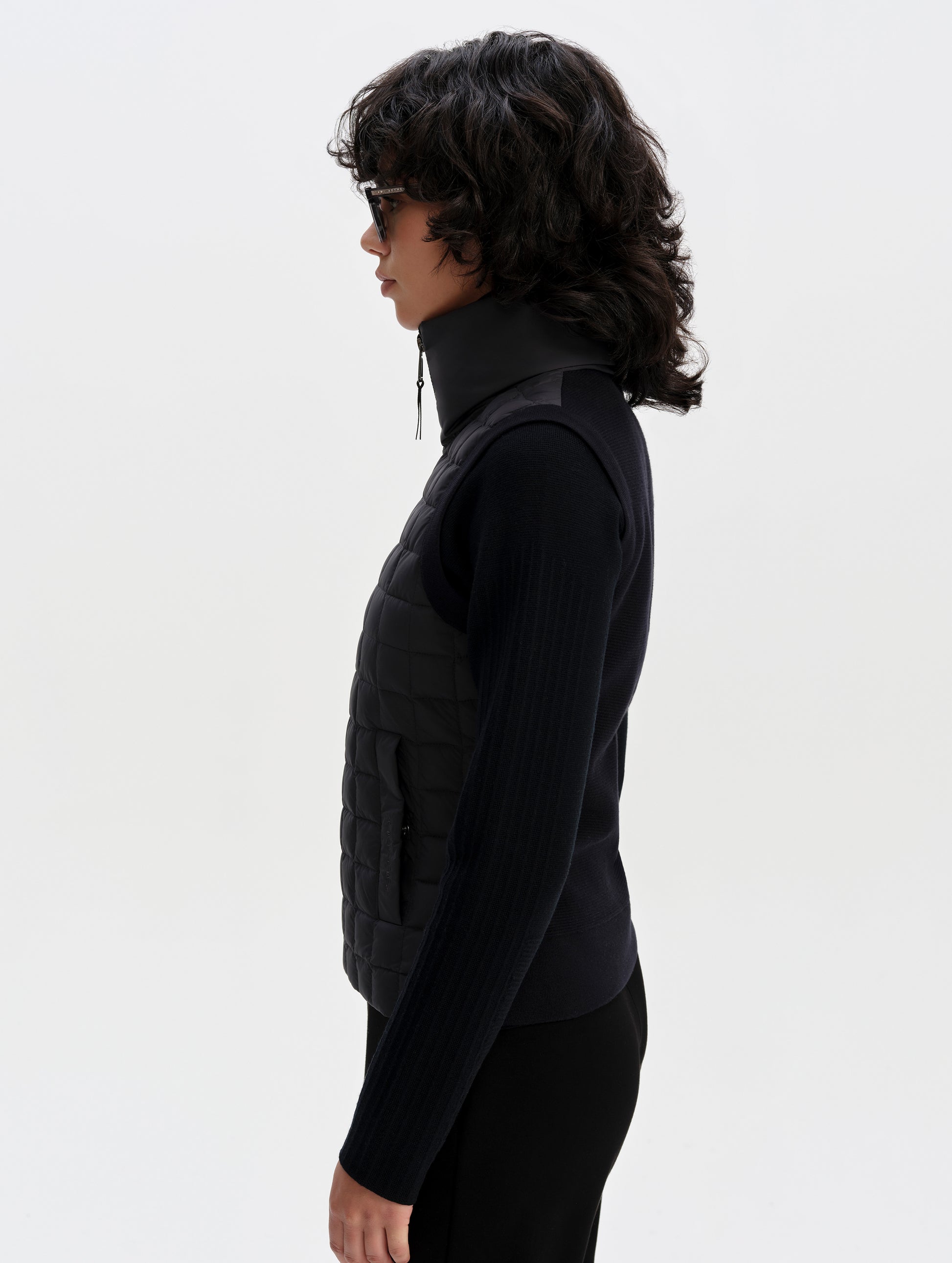 Side profile upper-body view of woman wearing the Phase Vest in Onyx Black from AETHER Apparel.