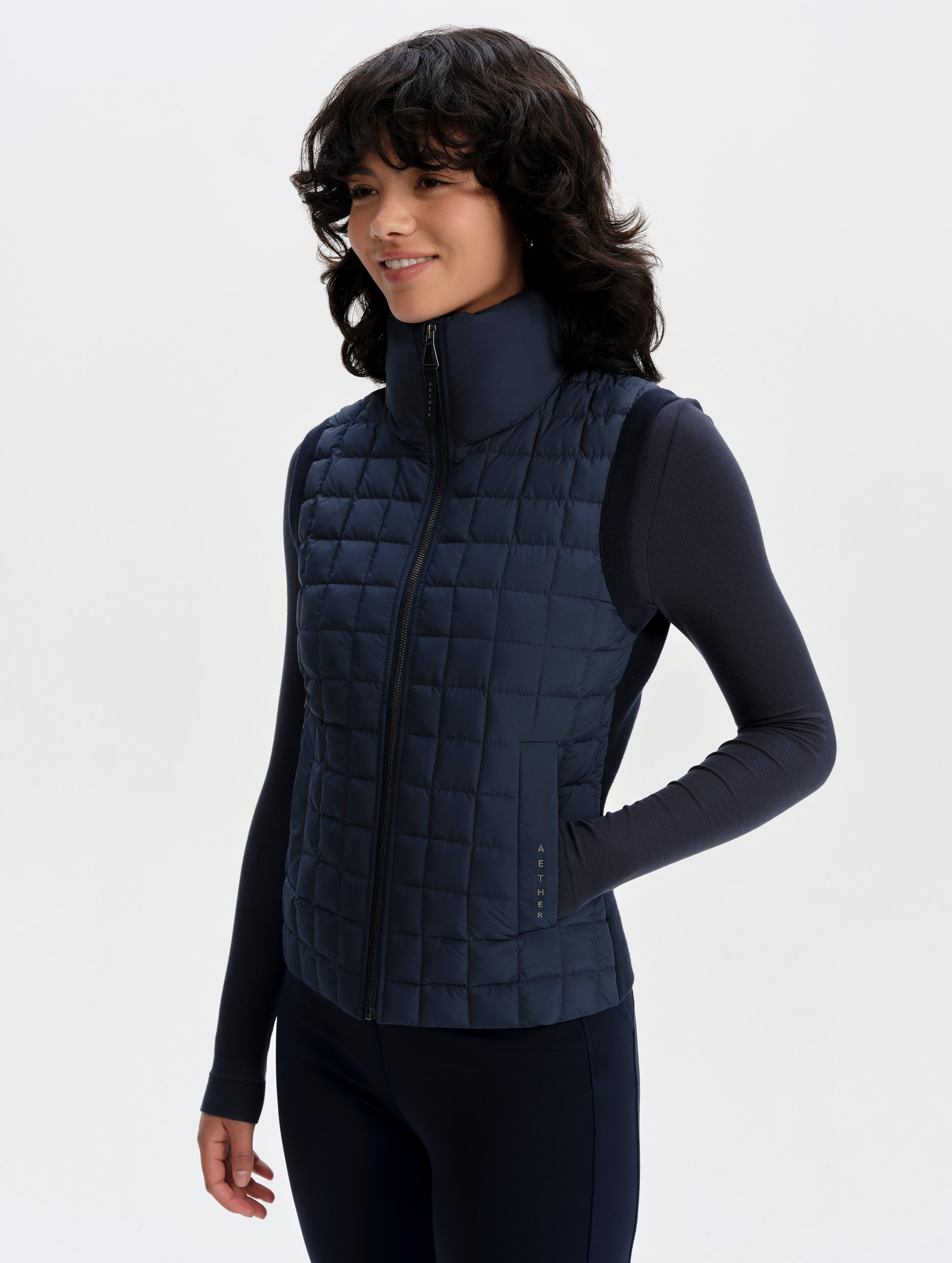 Front 3/4 upper-body view of woman wearing the Phase Vest in Total Eclipse from AETHER Apparel.