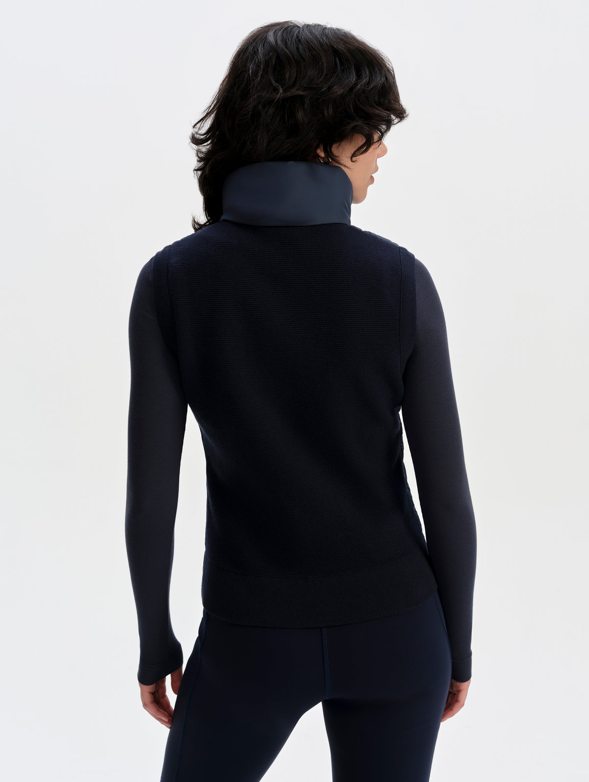 Rear upper-body view of woman wearing the Phase Vest in Total Eclipse from AETHER Apparel.