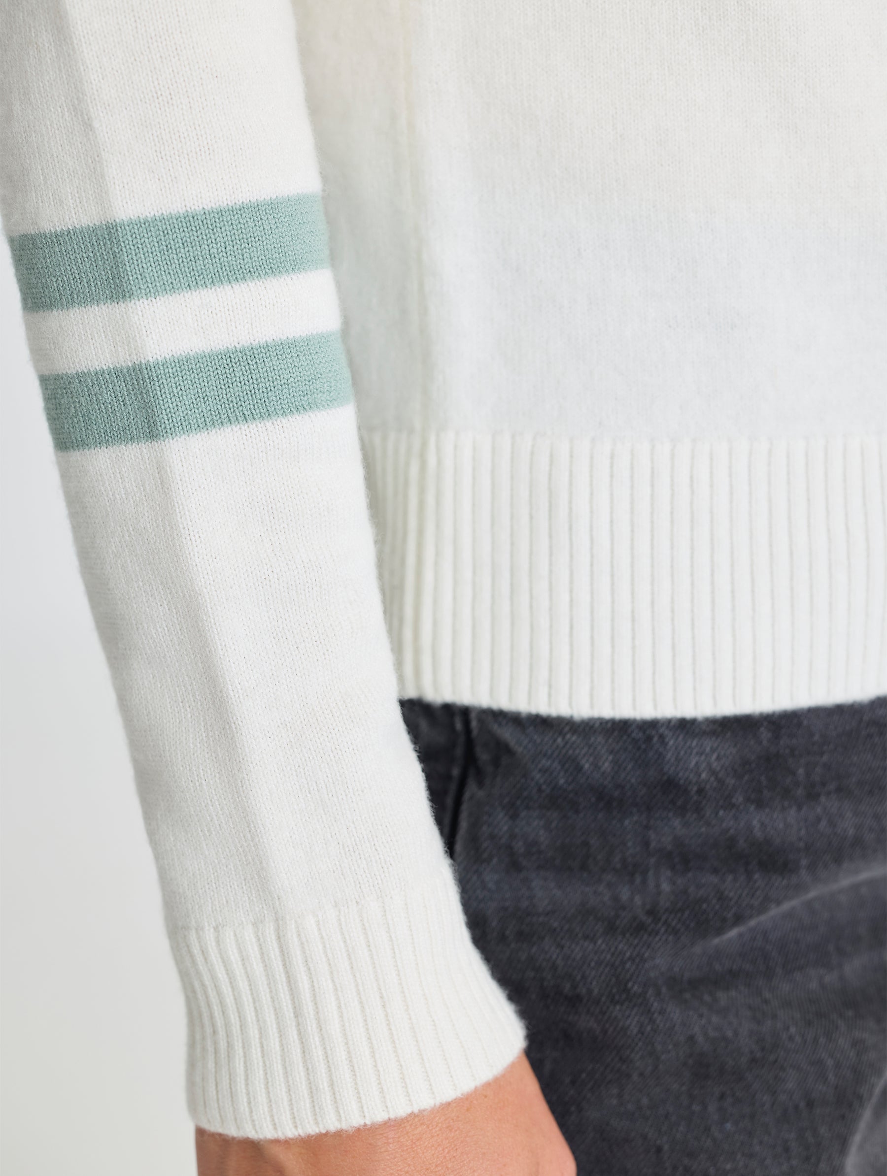 Closeup view of woman's right sleeve of Racer Sweater 2.0 in Winter White from AETHER Apparel (product available in Onyx Black).