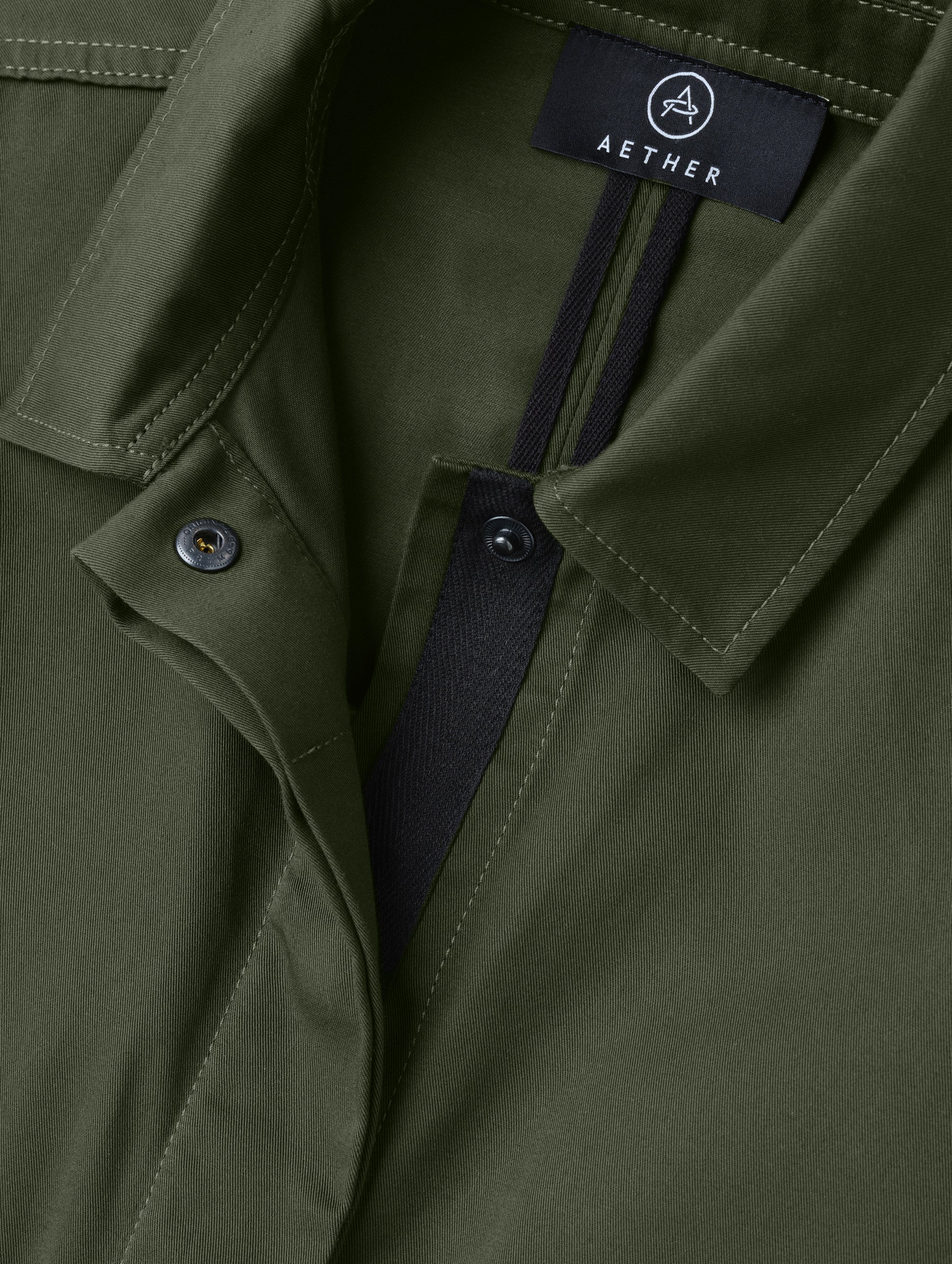 Closeup detailed view of the main center-front snap closure on the Raven Waxed Cotton Jacket in Forest Green from AETHER Apparel.