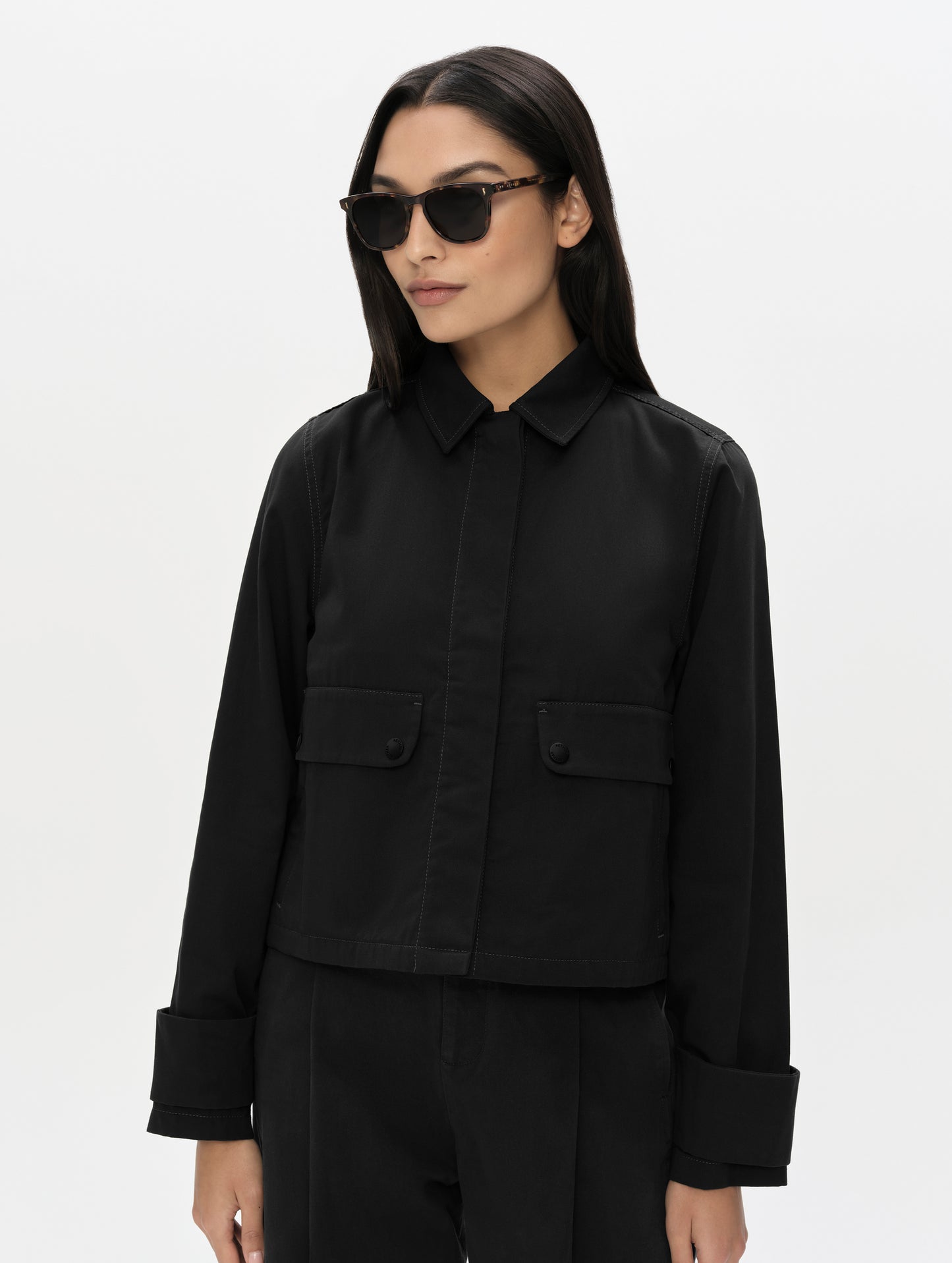 Front, upper-body view of woman wearing the Raven Waxed Cotton Jacket in Onyx Black from AETHER Apparel.