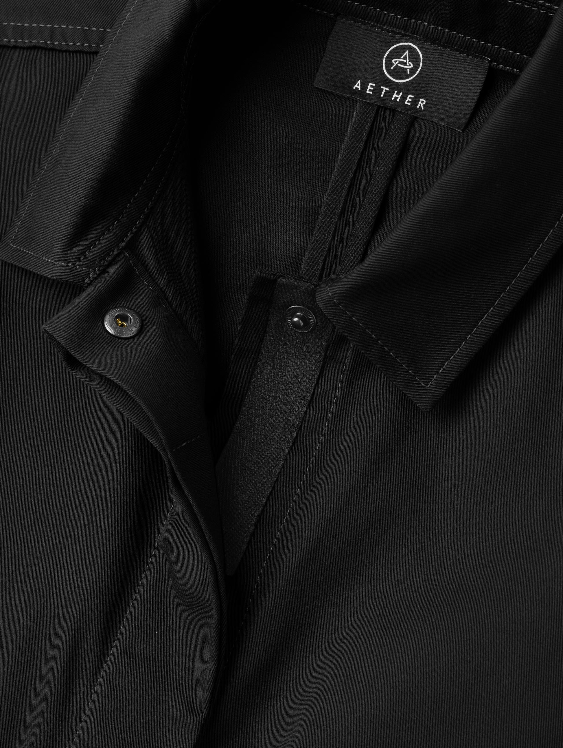 Closeup detailed view of the main center-front snap closure on the Raven Waxed Cotton Jacket in Onyx Black from AETHER Apparel.