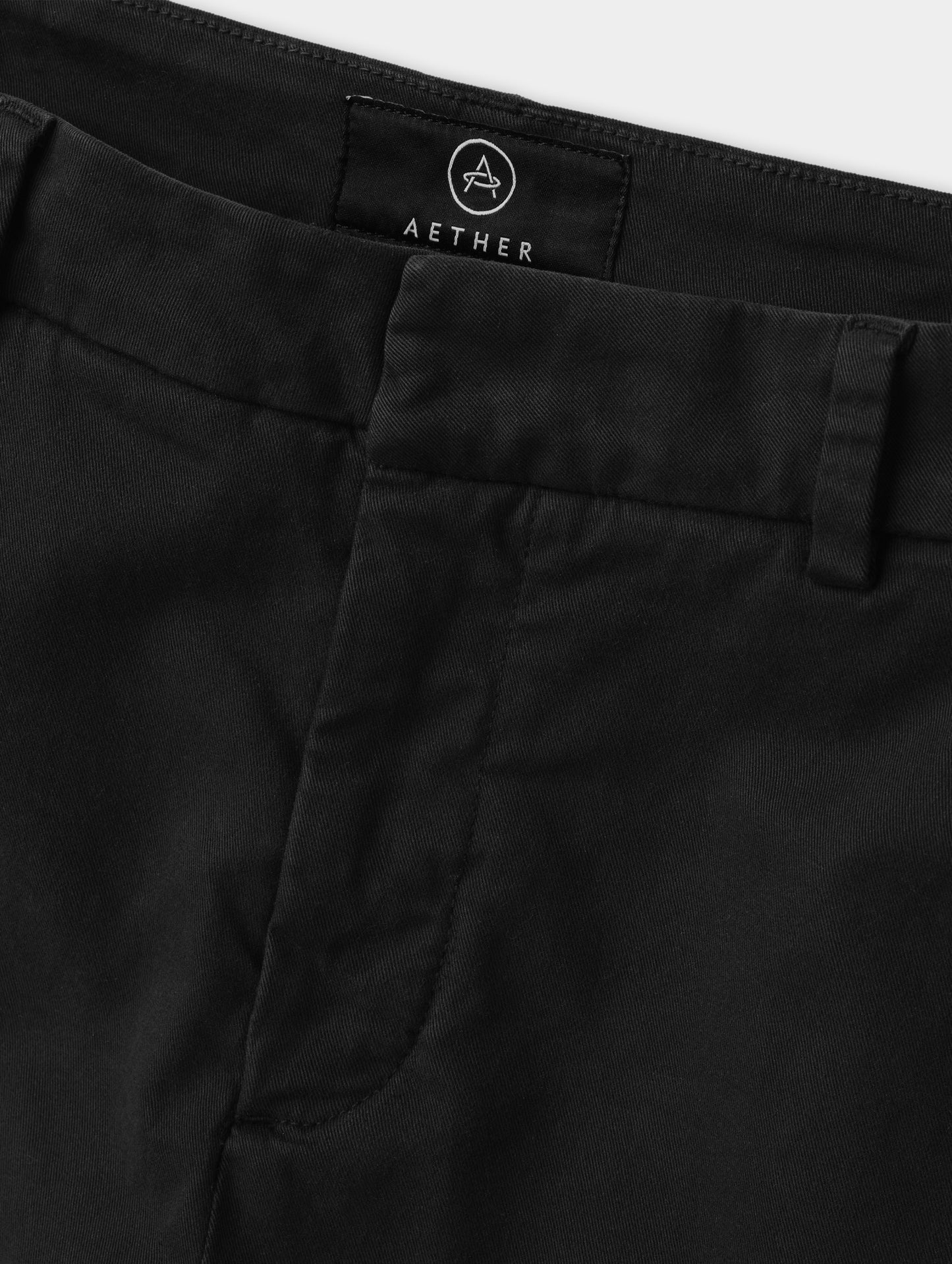 Closeup detailed view of the front closure and waistband on the Rhy Straight Leg Pant in Onyx Black from AETHER Apparel.