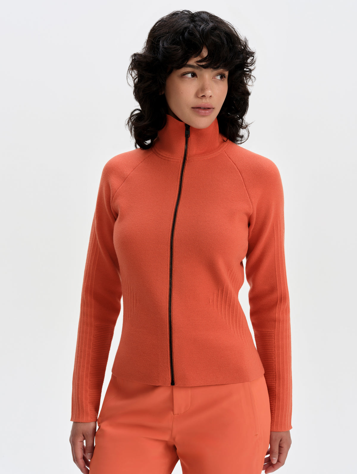 Front upper-body view of woman wearing the Riley Full-Zip Sweater 2.0 in Madeira Orange from AETHER Apparel.