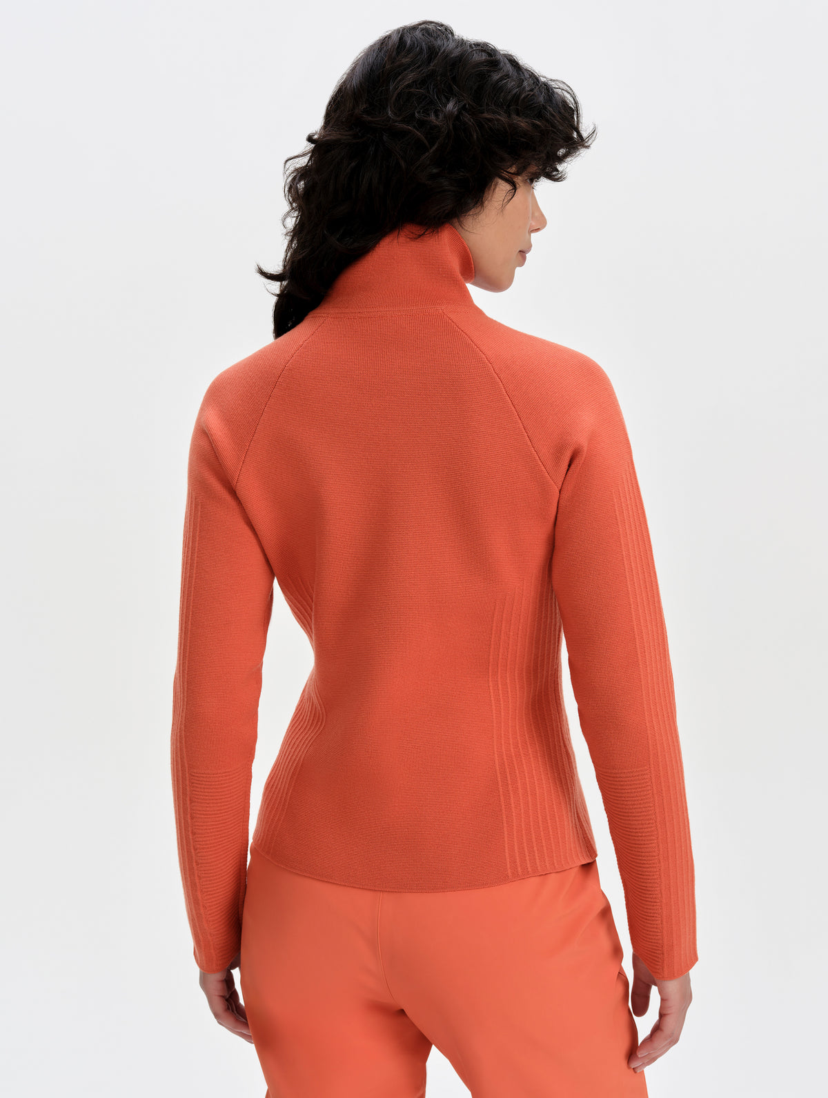 Rear upper-body view of woman wearing the Riley Full-Zip Sweater 2.0 in Madeira Orange from AETHER Apparel.