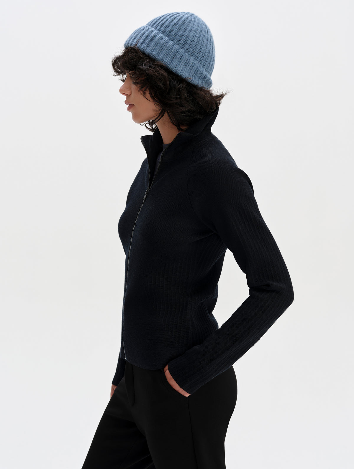 Side profile upper-body view of woman wearing the Riley Full-Zip Sweater 2.0 in Onyx Black from AETHER Apparel.
