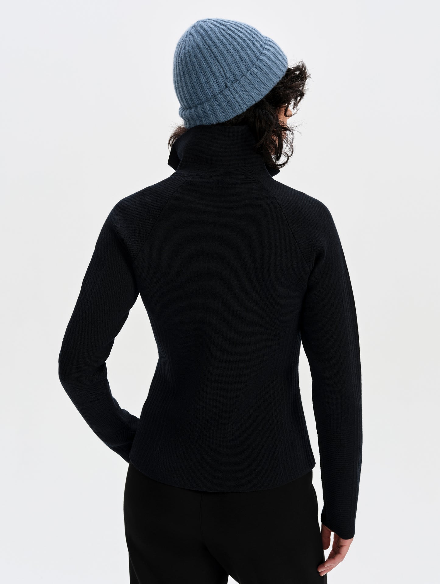Rear upper-body view of woman wearing the Riley Full-Zip Sweater 2.0 in Onyx Black from AETHER Apparel.