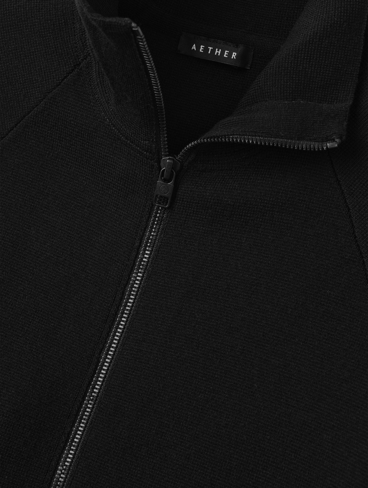 Flat lay view of the center-front zipper on the Riley Full-Zip Sweater 2.0 in Onyx Black from AETHER Apparel.