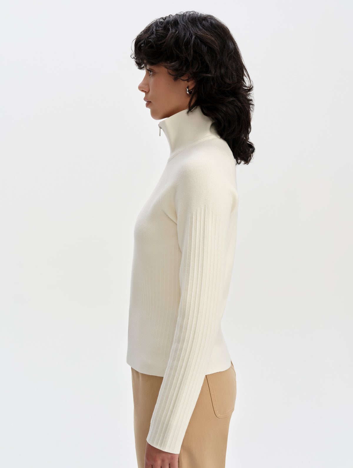 Side profile upper-body view of woman wearing the Riley Full-Zip Sweater 2.0 in Winter White from AETHER Apparel.