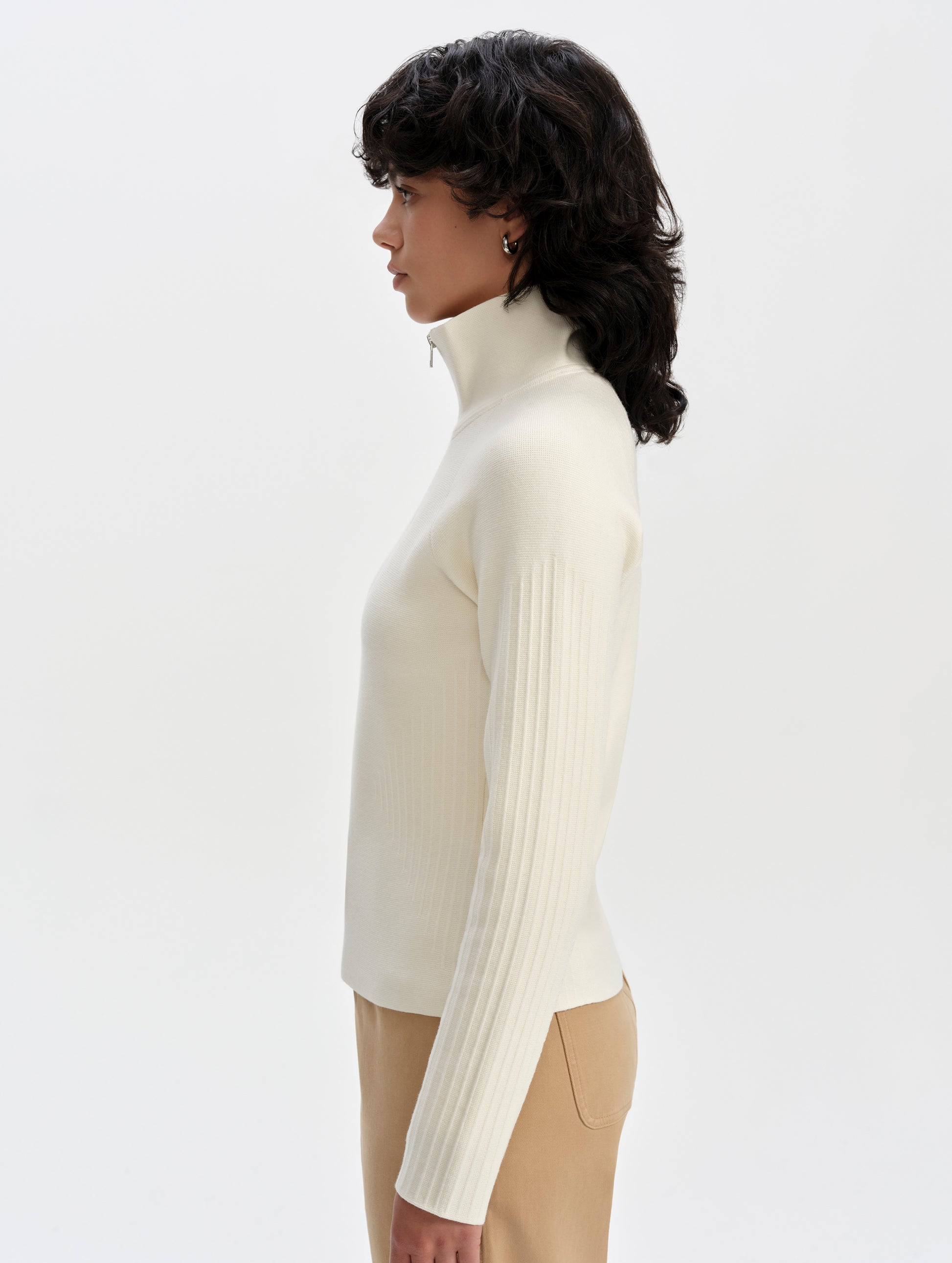 Side profile upper-body view of woman wearing the Riley Full-Zip Sweater 2.0 in Winter White from AETHER Apparel.