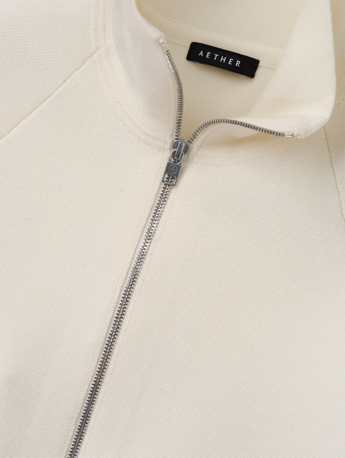 Flat lay view of the center-front zipper on the Riley Full-Zip Sweater 2.0 in Winter White from AETHER Apparel.