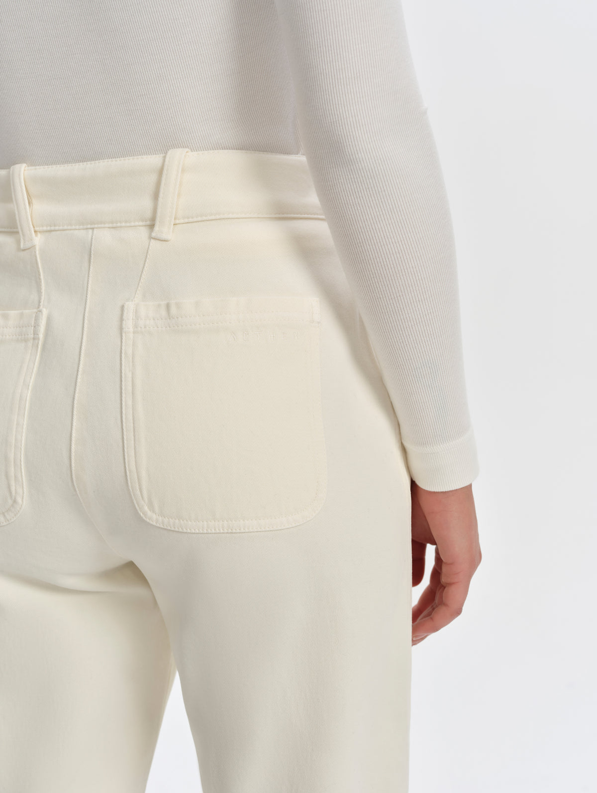 Closeup detailed view of the angled rear belt loops and rounded back patch pockets on the Rowan Cotton Pant in Winter White from AETHER Apparel.