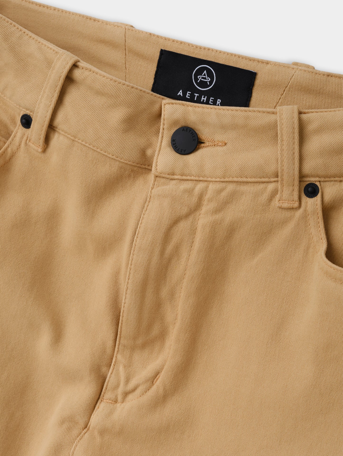 Closeup detailed view of the zipper fly and shank button closure on the Rowan Cotton Pant in Latte Brown from AETHER Apparel.