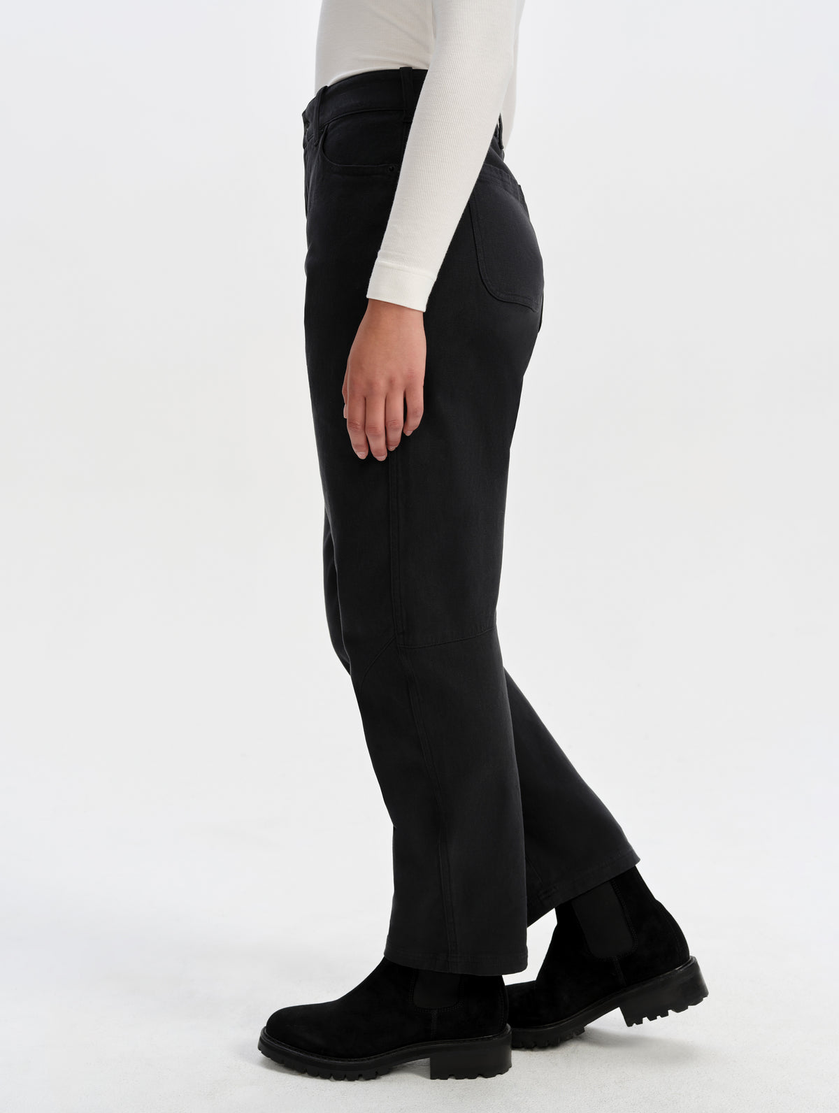 Side profile lower-body view of woman wearing the Rowan Cotton Pant in Onyx Black from AETHER Apparel.