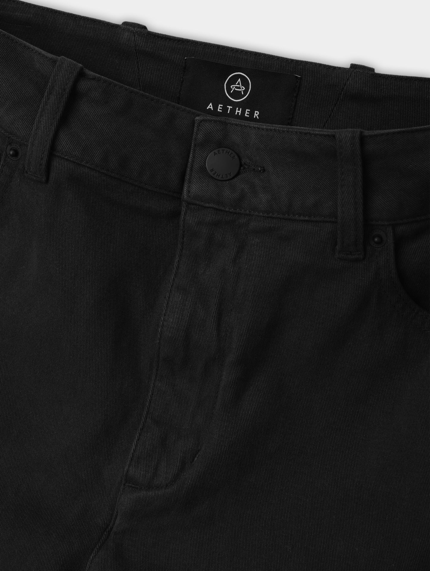 Closeup detailed view of the zipper fly and shank button closure on the Rowan Cotton Pant in Onyx Black from AETHER Apparel.